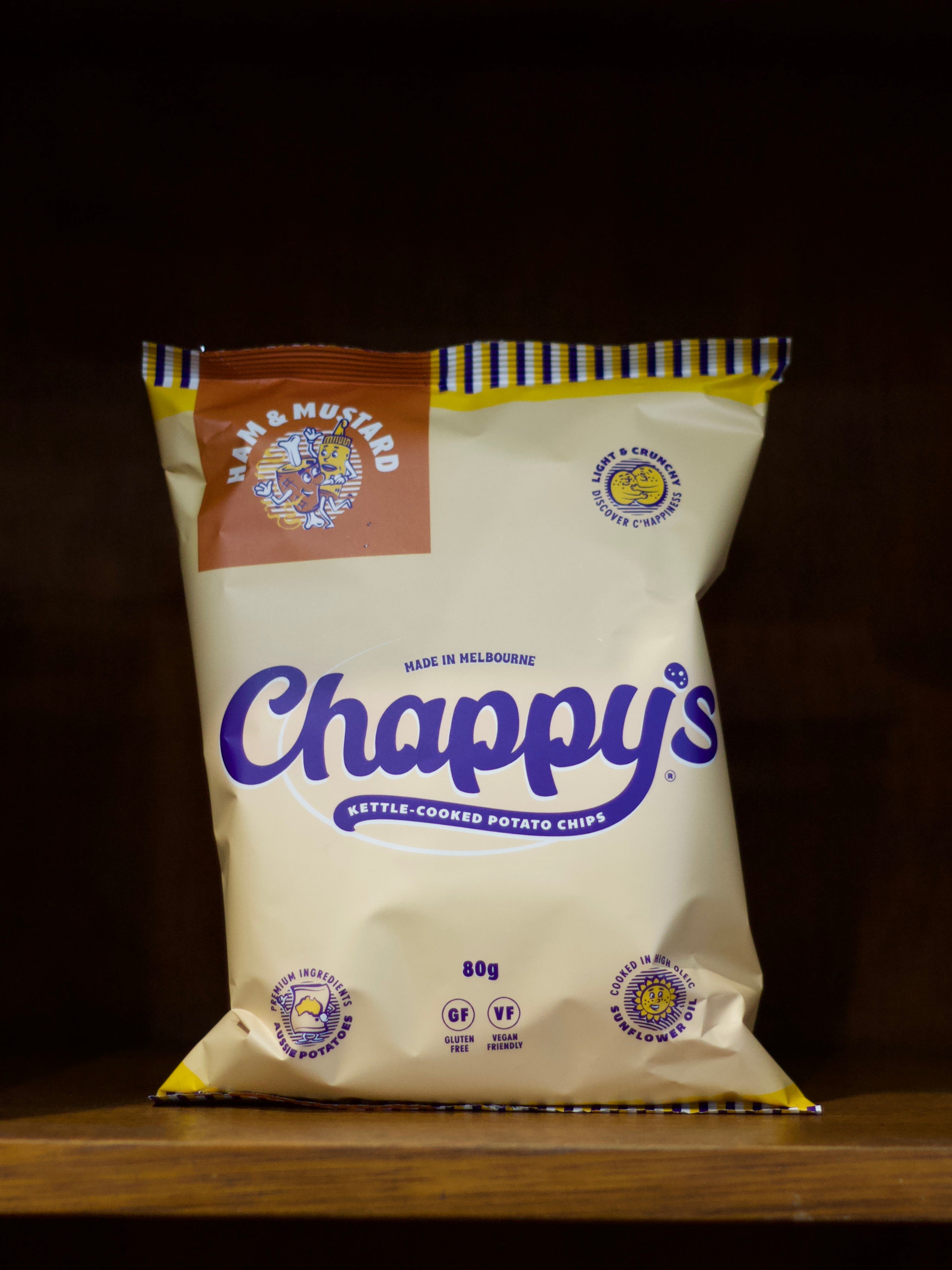 Bag of Ham & Mustard flavoured Chappy's kettle-cooked potato chips on a wooden surface with a dark background