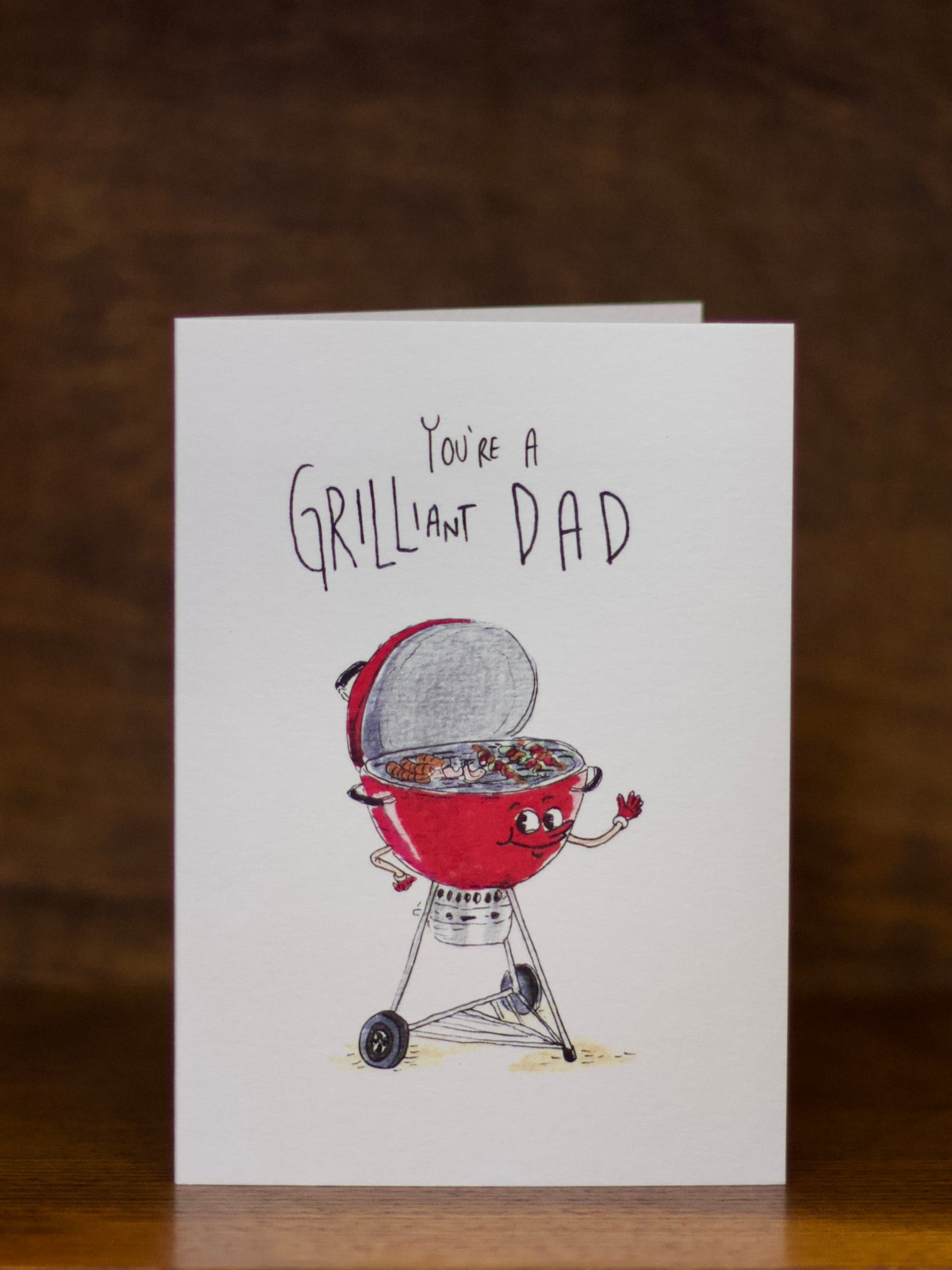 Dad greeting card with a grill illustration and text 'You're a Grilliant Dad' on a dark background