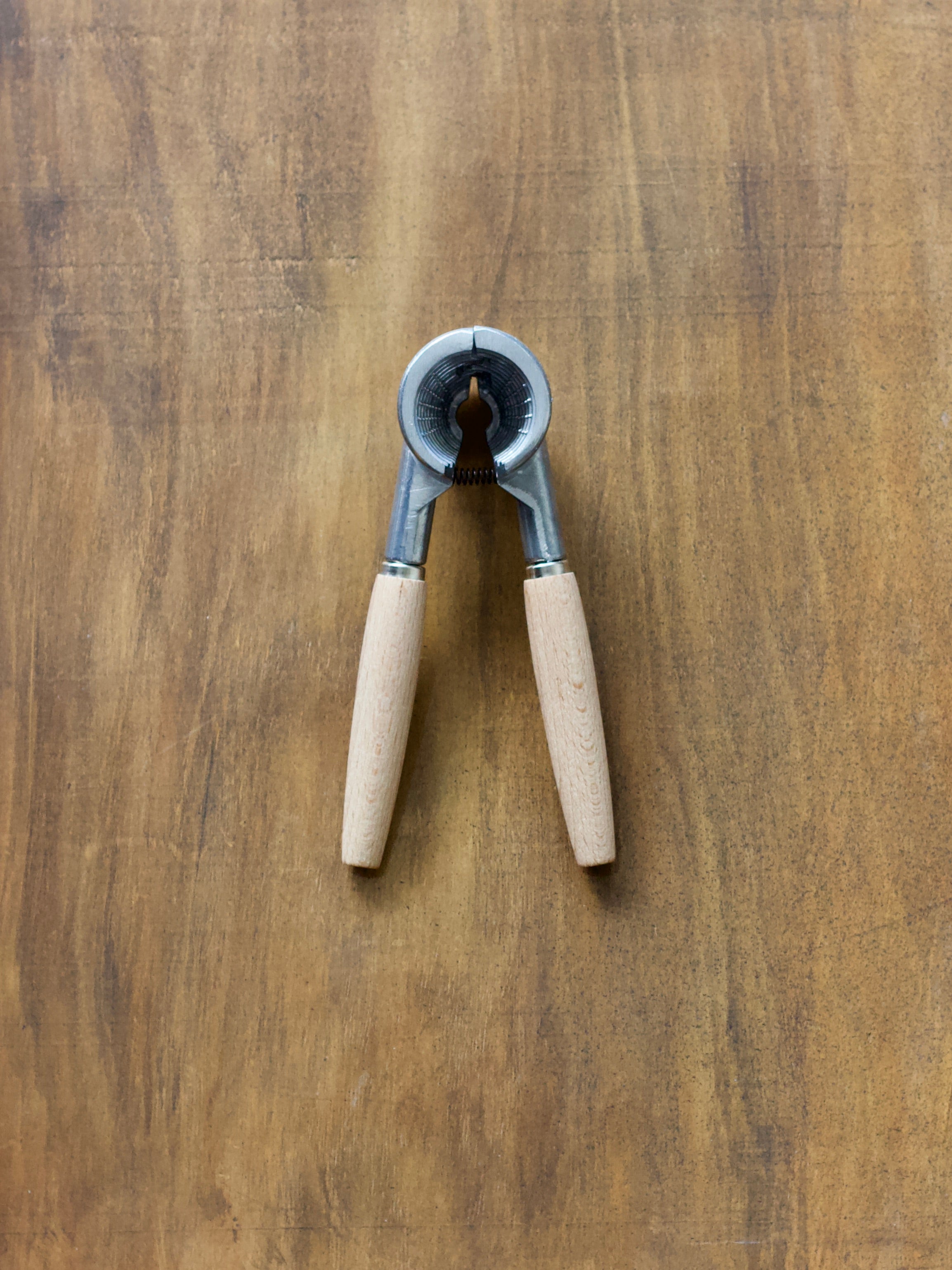 Manual nutcracker with wooden handles on a wooden surface