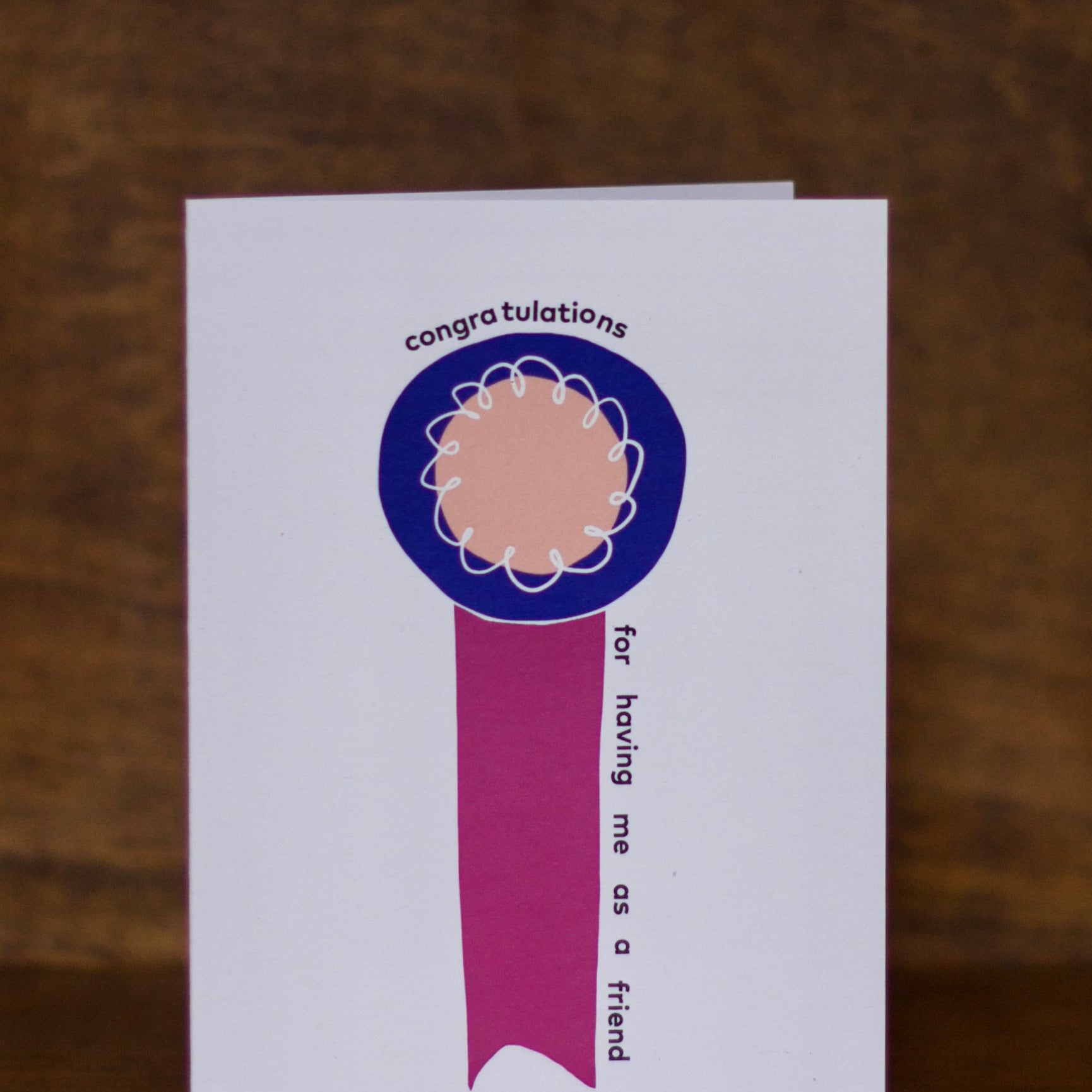 Congratulations greeting card with a blue ribbon design on a wooden surface