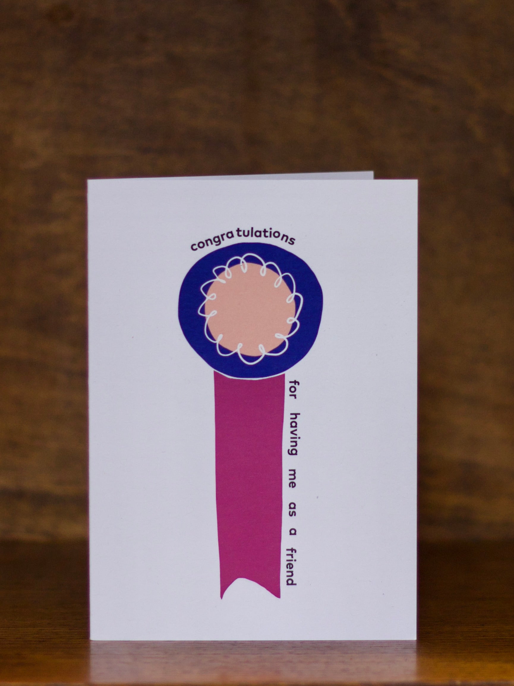 Congratulations greeting card with a blue ribbon design on a wooden surface