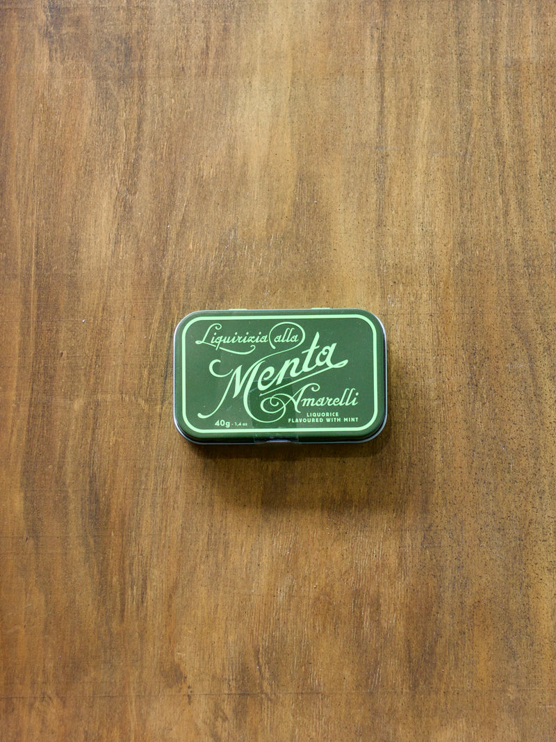 Green tin box with Liquorificio della Menta Amarelli inside on a wooden surface