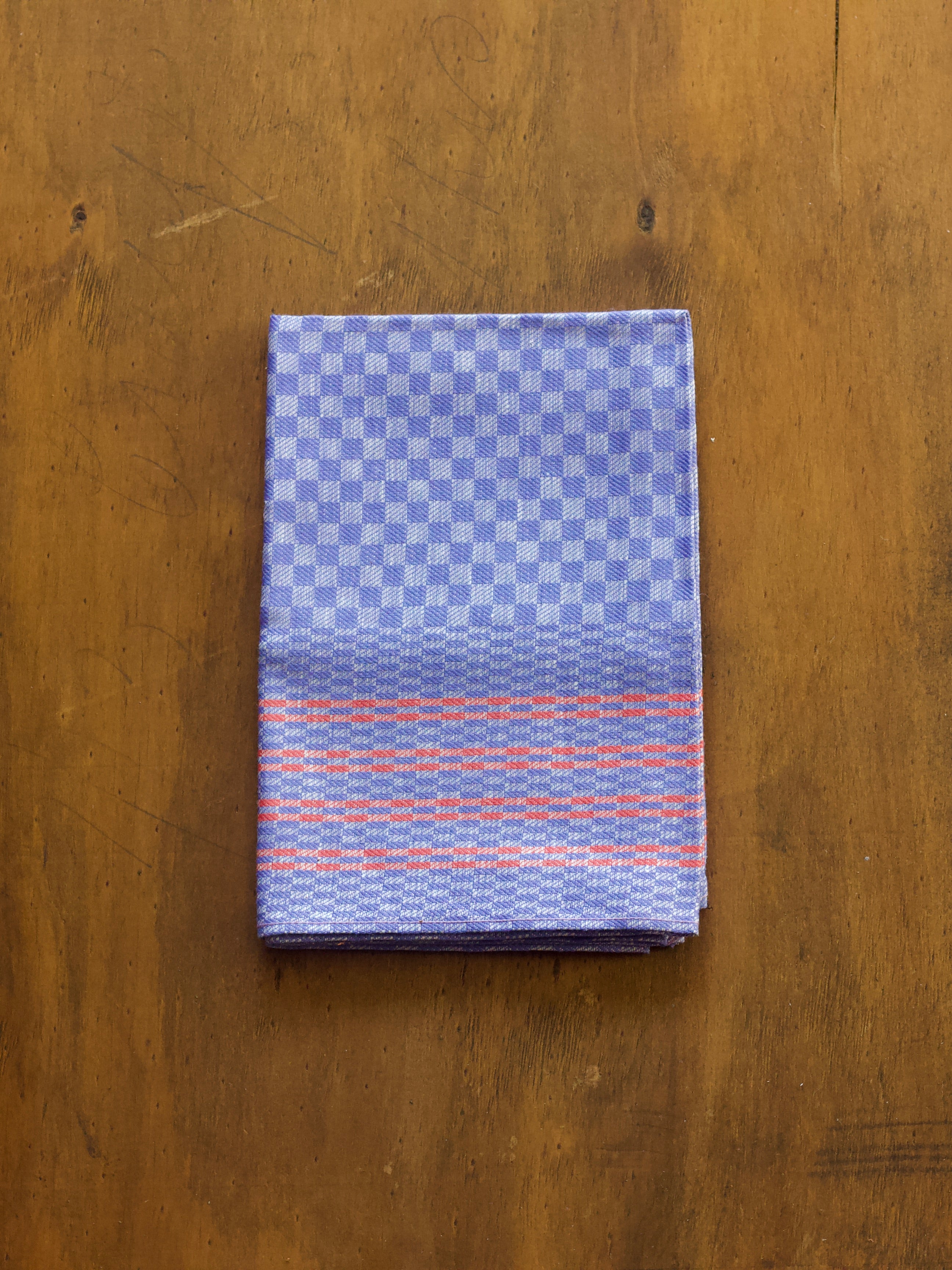 Redecker folded oversized tea towel fabric with blue and orange pattern on a wooden surface