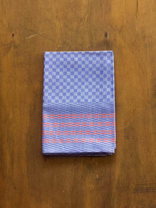 Redecker folded oversized tea towel fabric with blue and orange pattern on a wooden surface