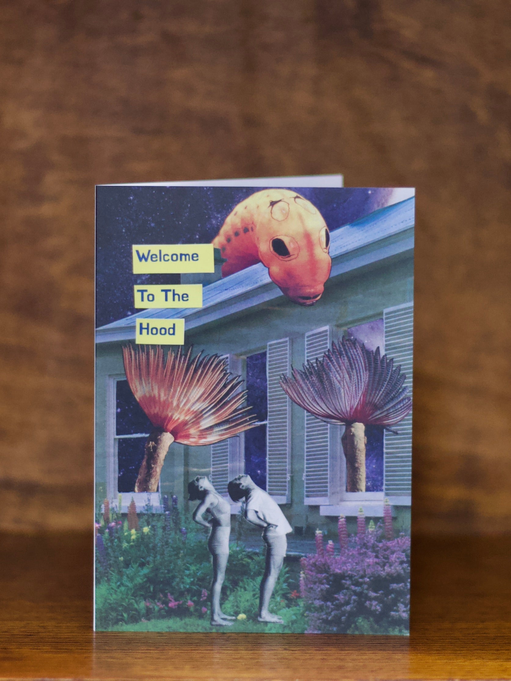 Housewarming greeting card with artistic design of people and plants on a wooden surface