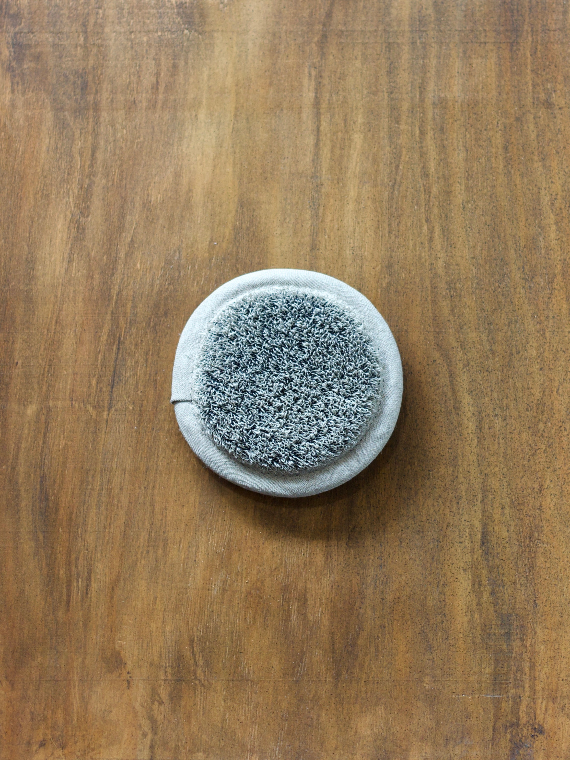 Round linen sponge on a wooden surface