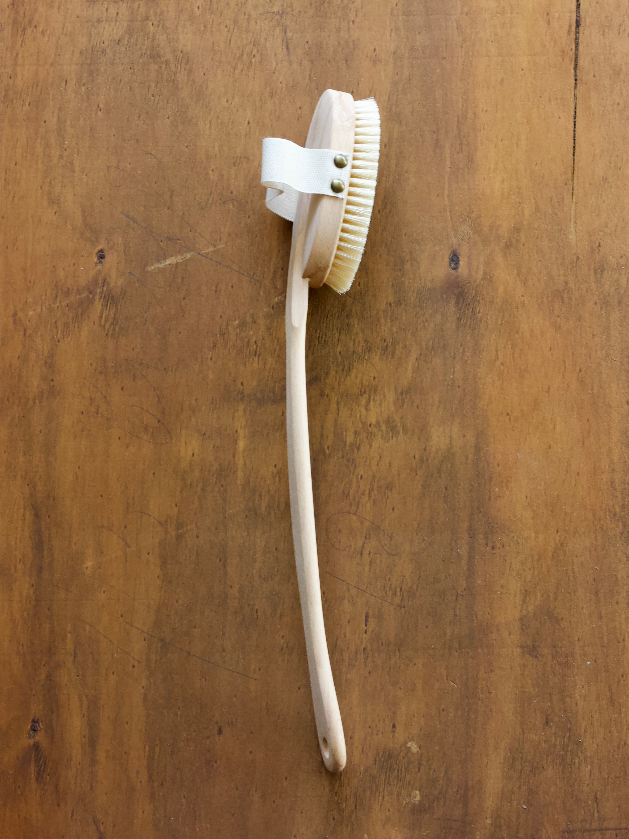 Massage brush with a long handle on a wooden surface
