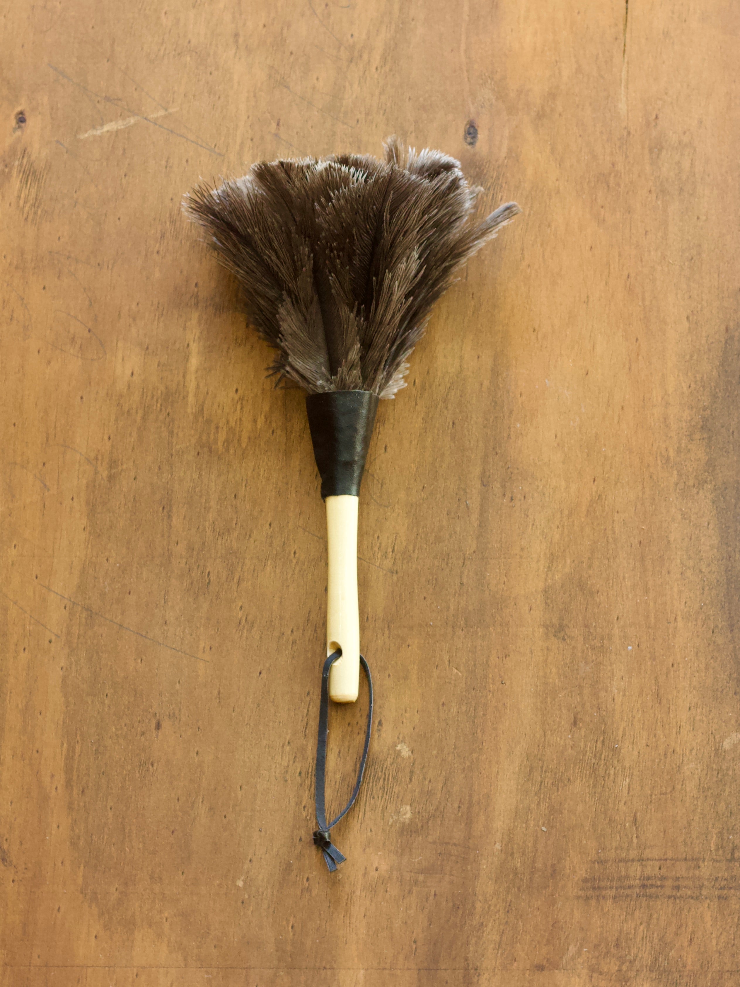 Redecker Feather Duster with a wooden handle on a wooden surface