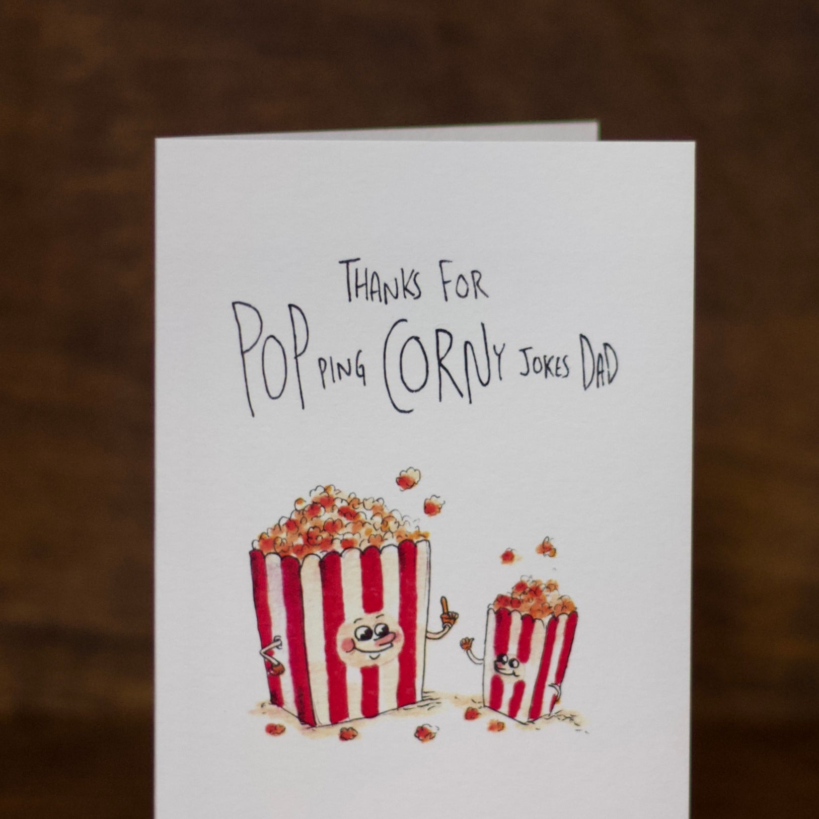 Dad greeting card with popcorn illustration and text on a wooden surface