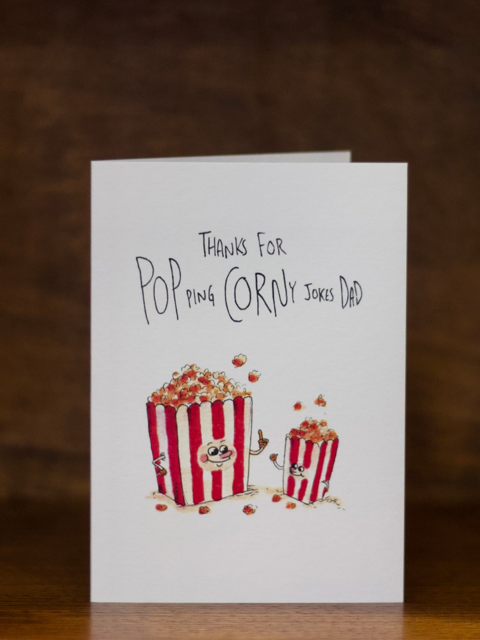 Dad greeting card with popcorn illustration and text on a wooden surface