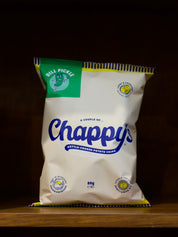 Bag of Dill Pickle Flavoured Chappy's kettle-cooked potato chips on a wooden surface with a dark background