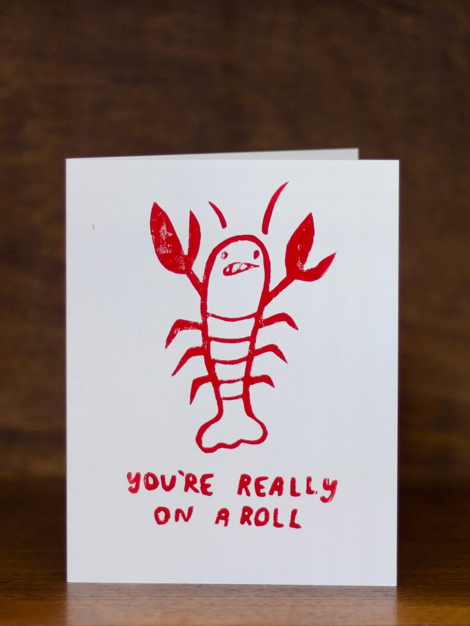 Congratulations greeting card with red lobster illustration and text 'You're really on a roll' on a white background