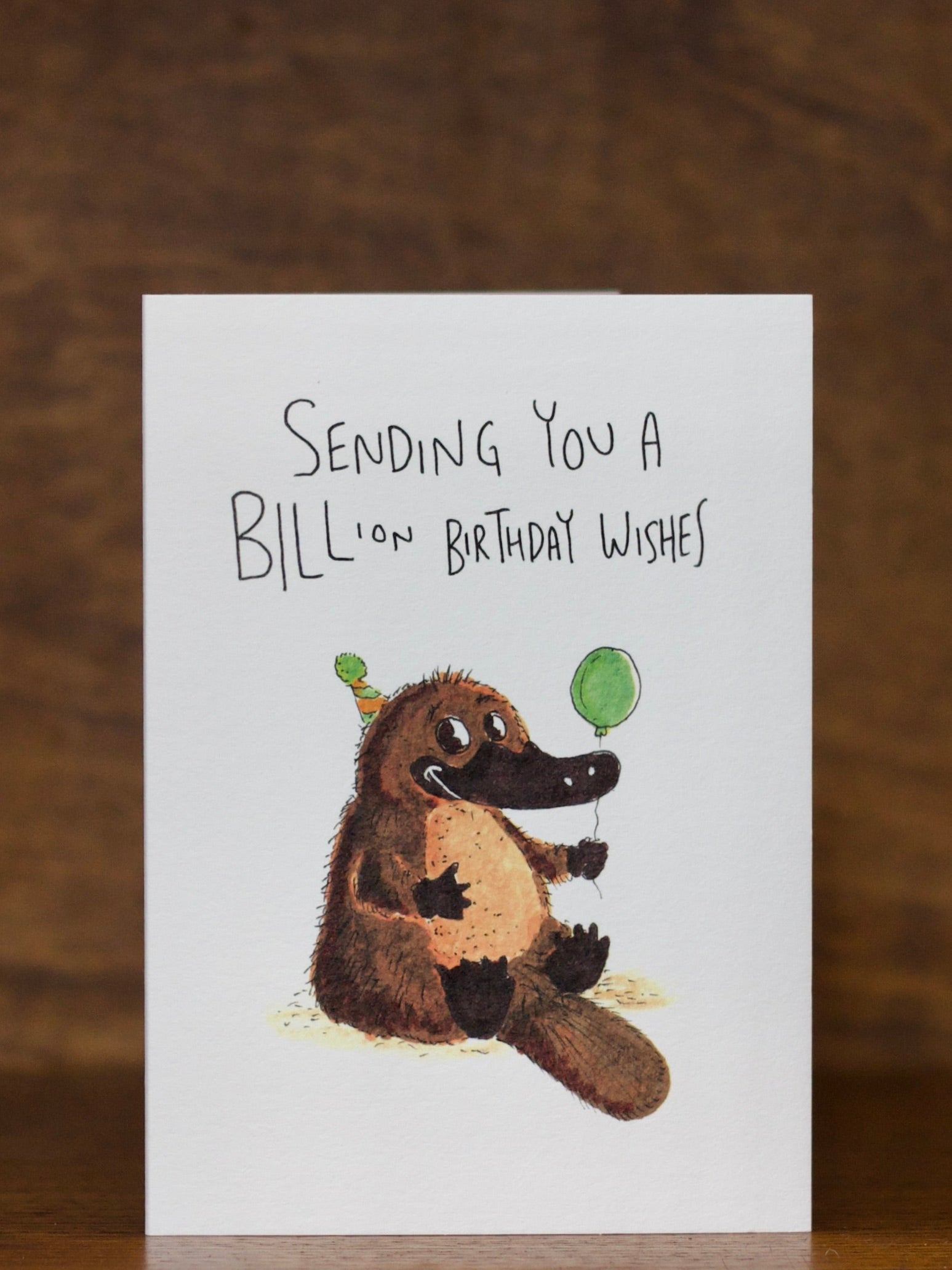 Birthday greeting cards by Well Drawn with a platypus illustration and text on a wooden surface