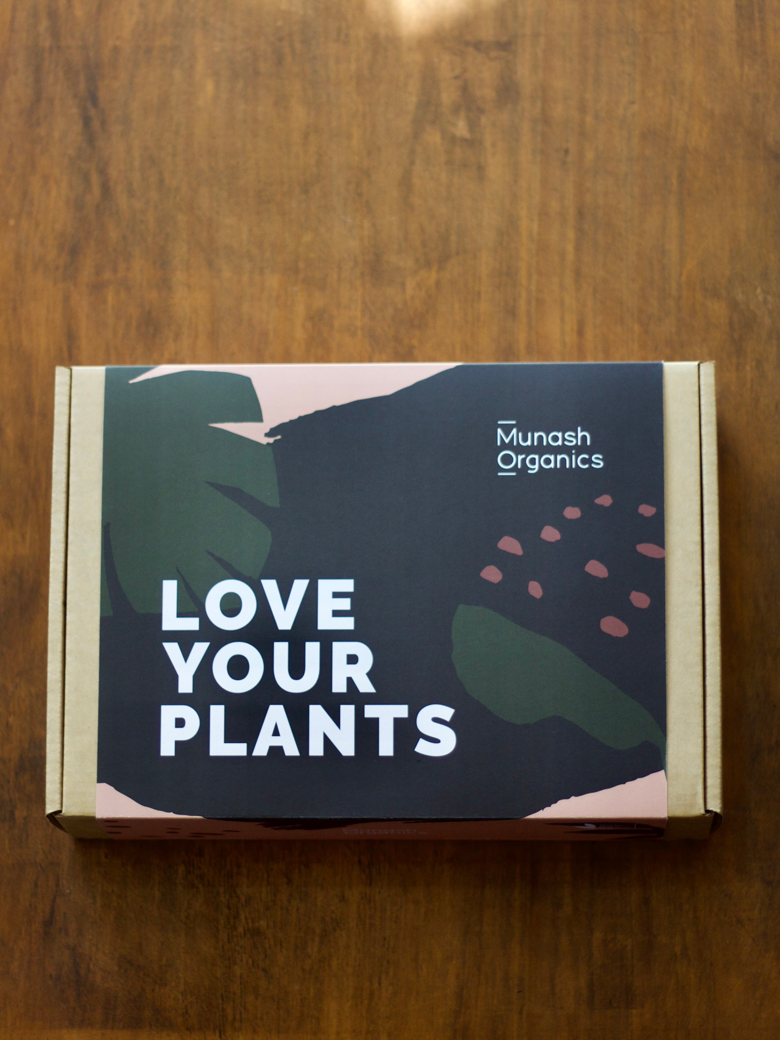 Munash Organics gift box for indoor plant care on a wooden surface.