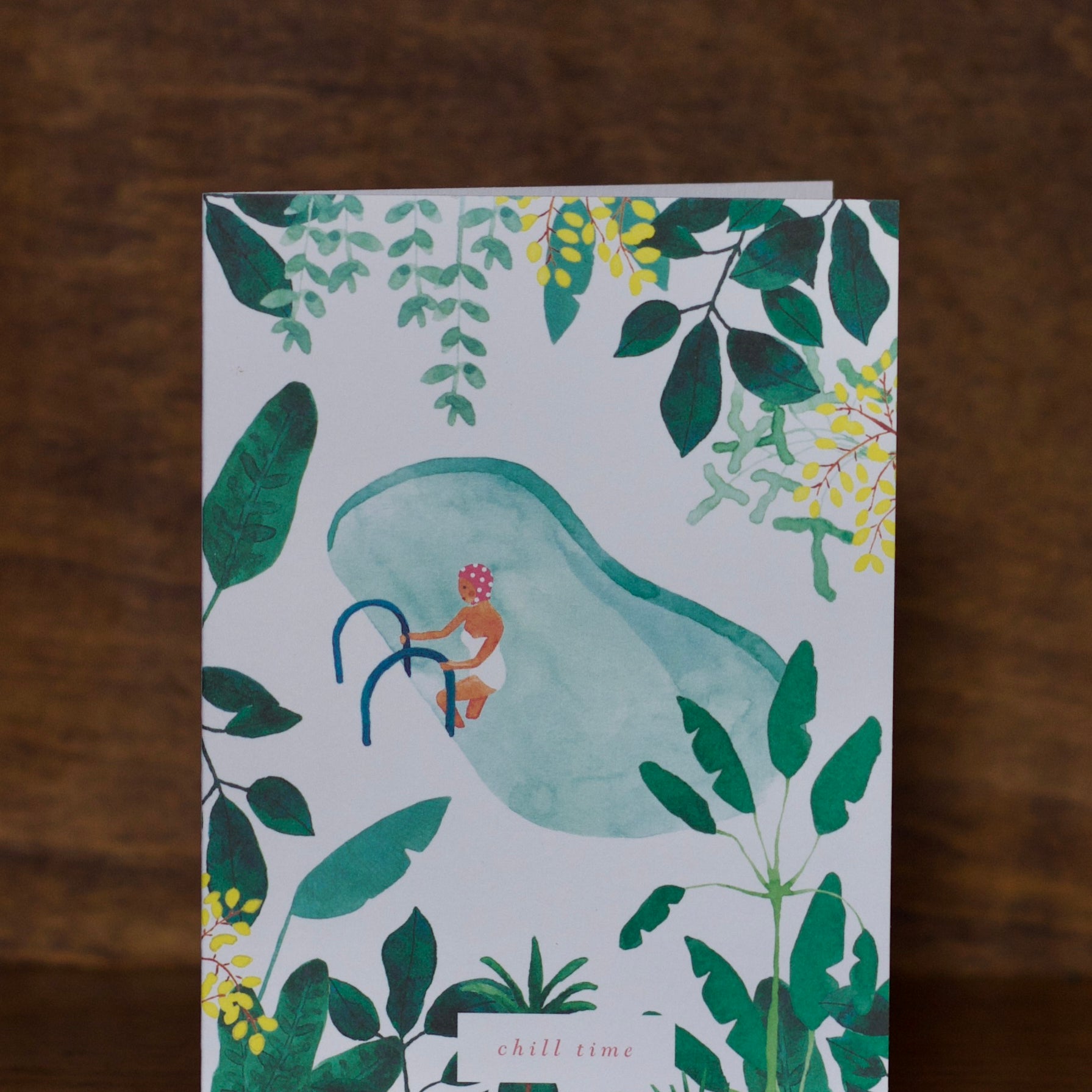 All Occasions greeting cards with a design of a person in a swimsuit with a surfboard, surrounded by green leaves and plants on a wooden surface.