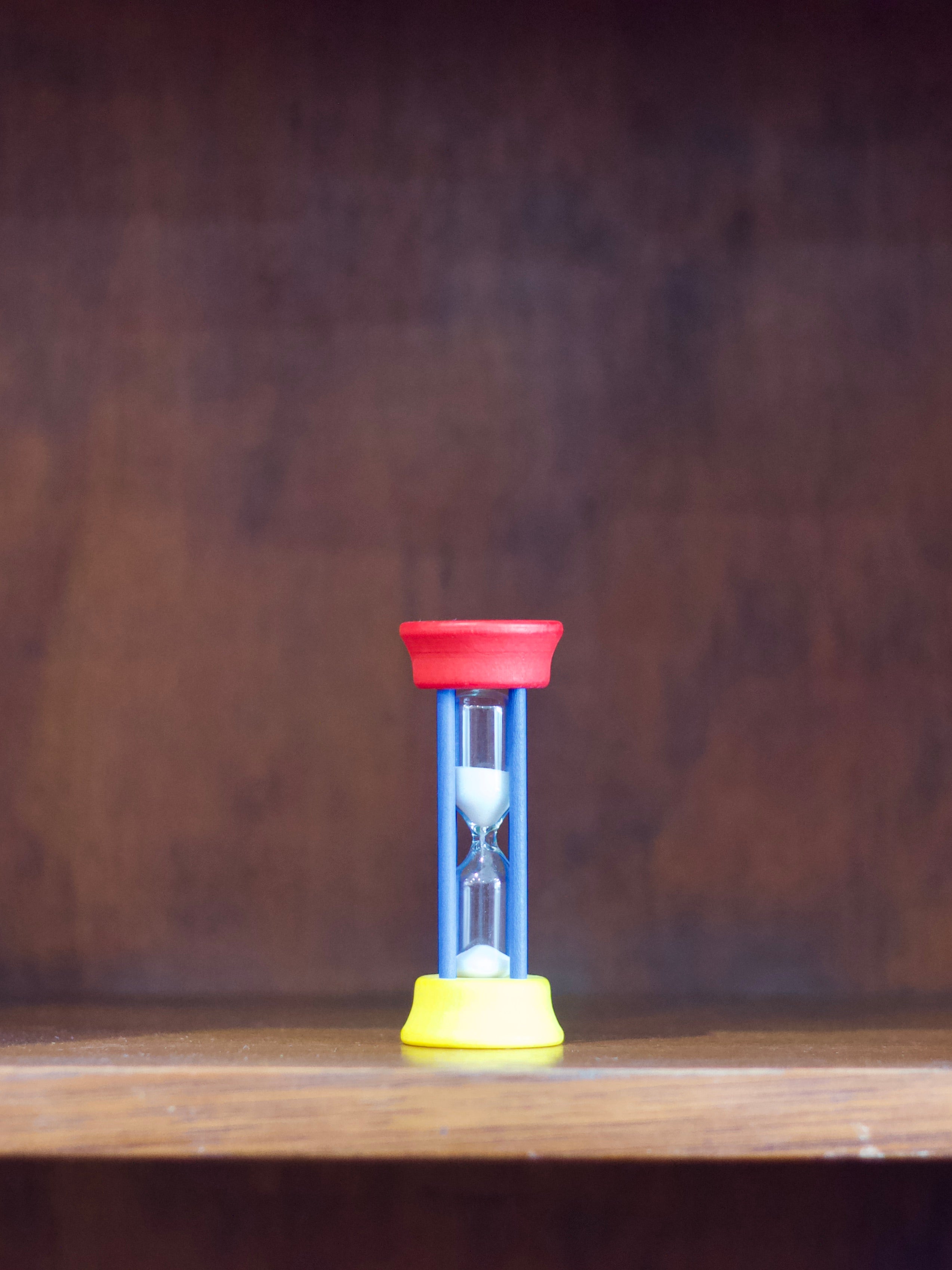 Redecker two minute sand timer with red top and yellow base on a wooden surface