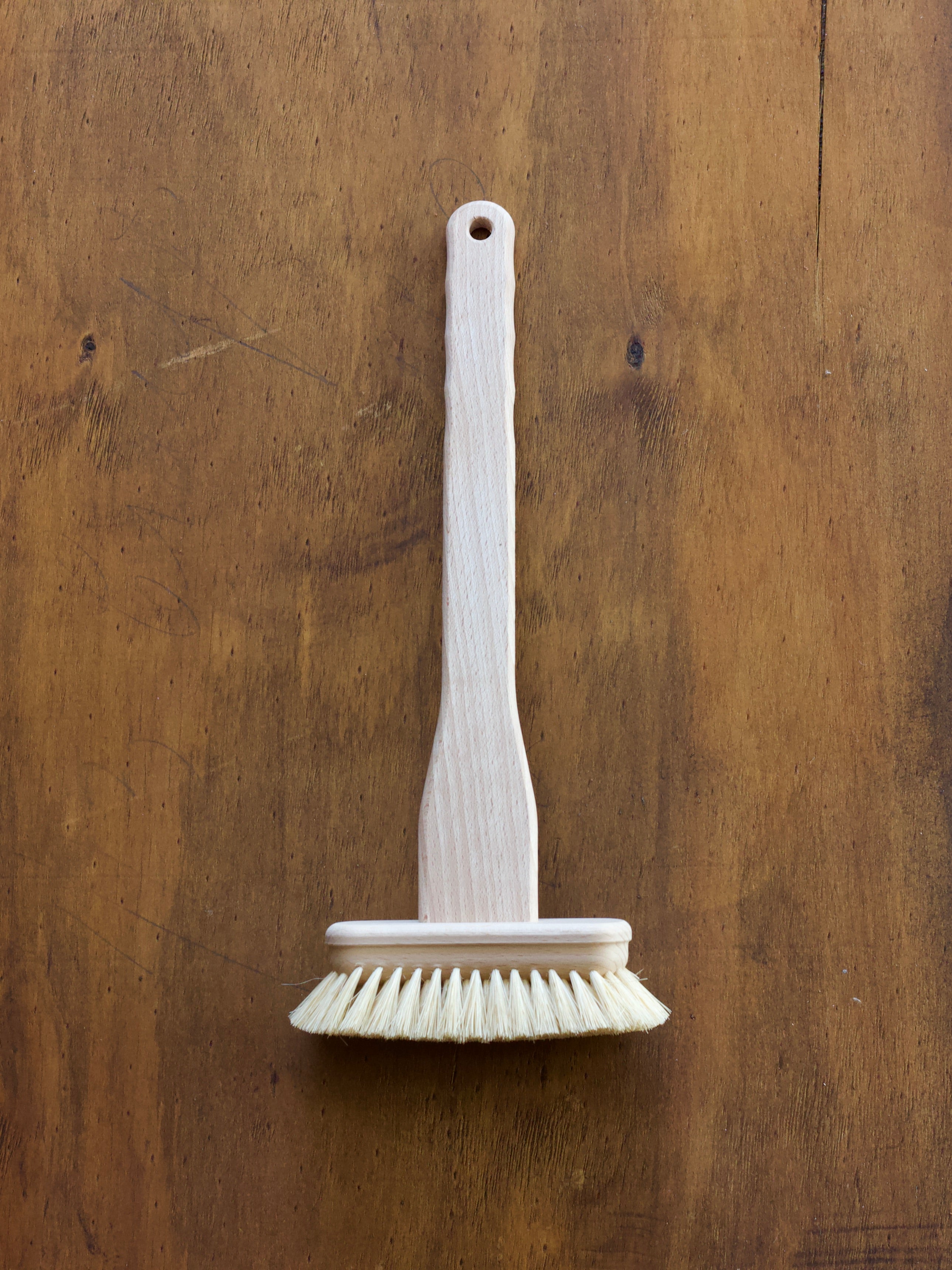 Tub Brush for cleaning the bath on a wooden surface.