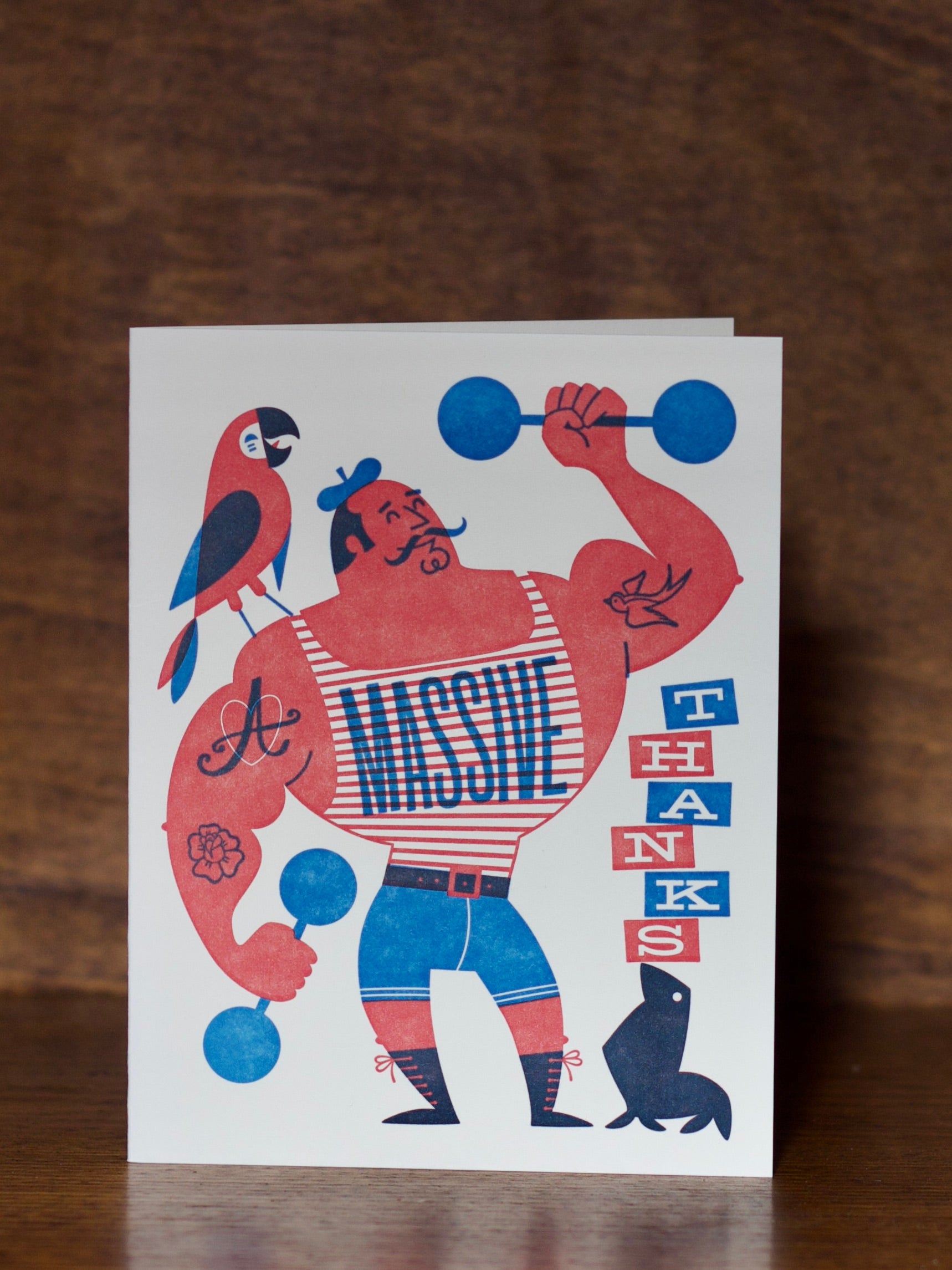 Thank you greeting cards with a muscular figure lifting weights, parrot, and text on a wooden surface