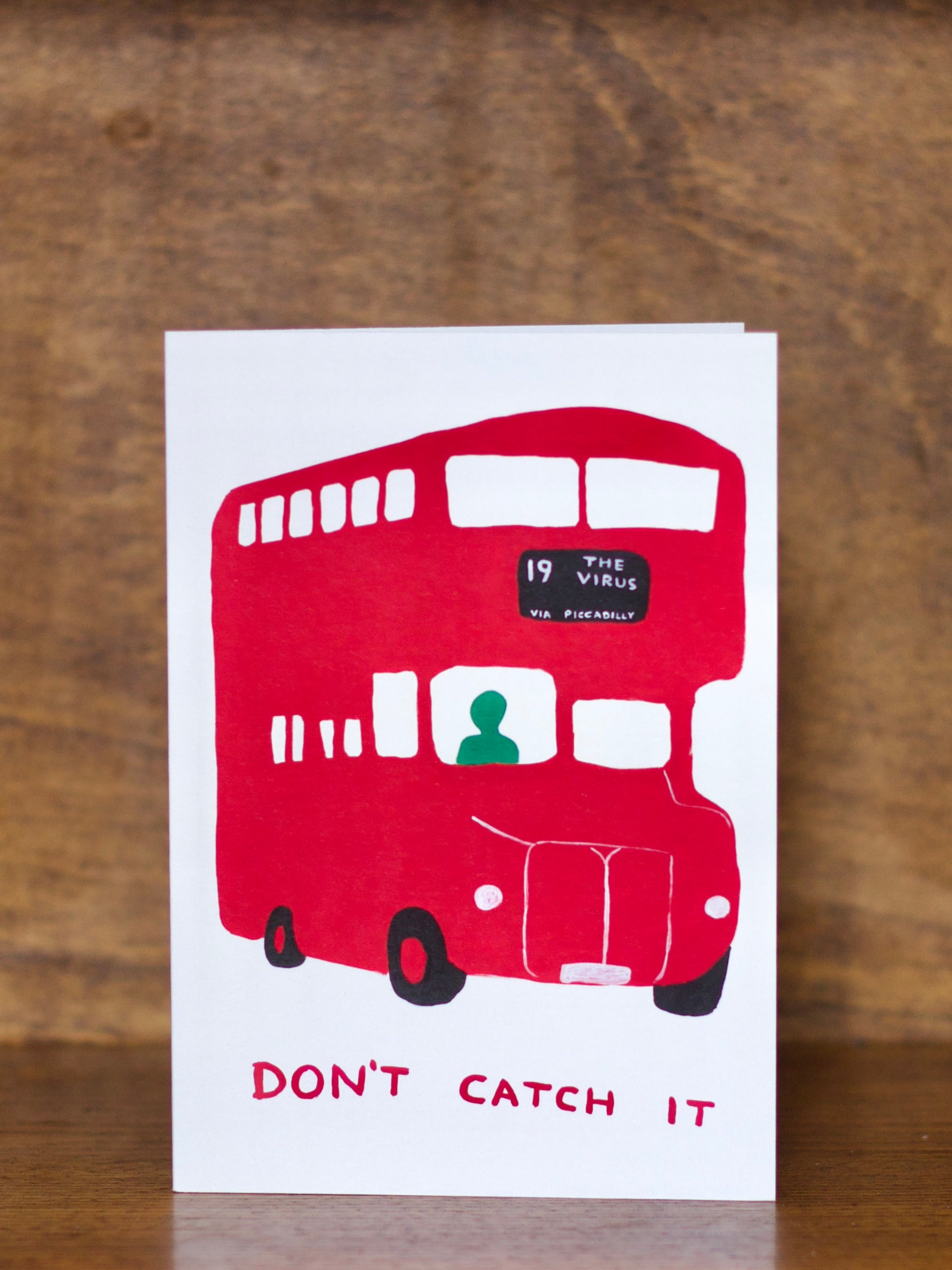 All occasions greeting card with a red double-decker bus illustration and text on a wooden background