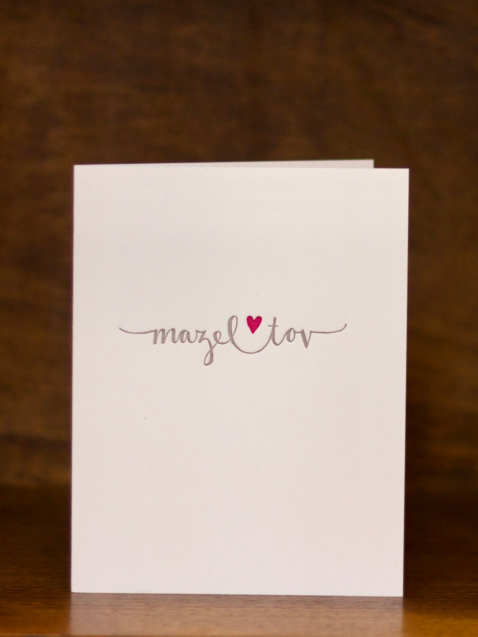 Mazel Tov Congratulations greeting card with 'mazel tov' text and a red heart on a brown background