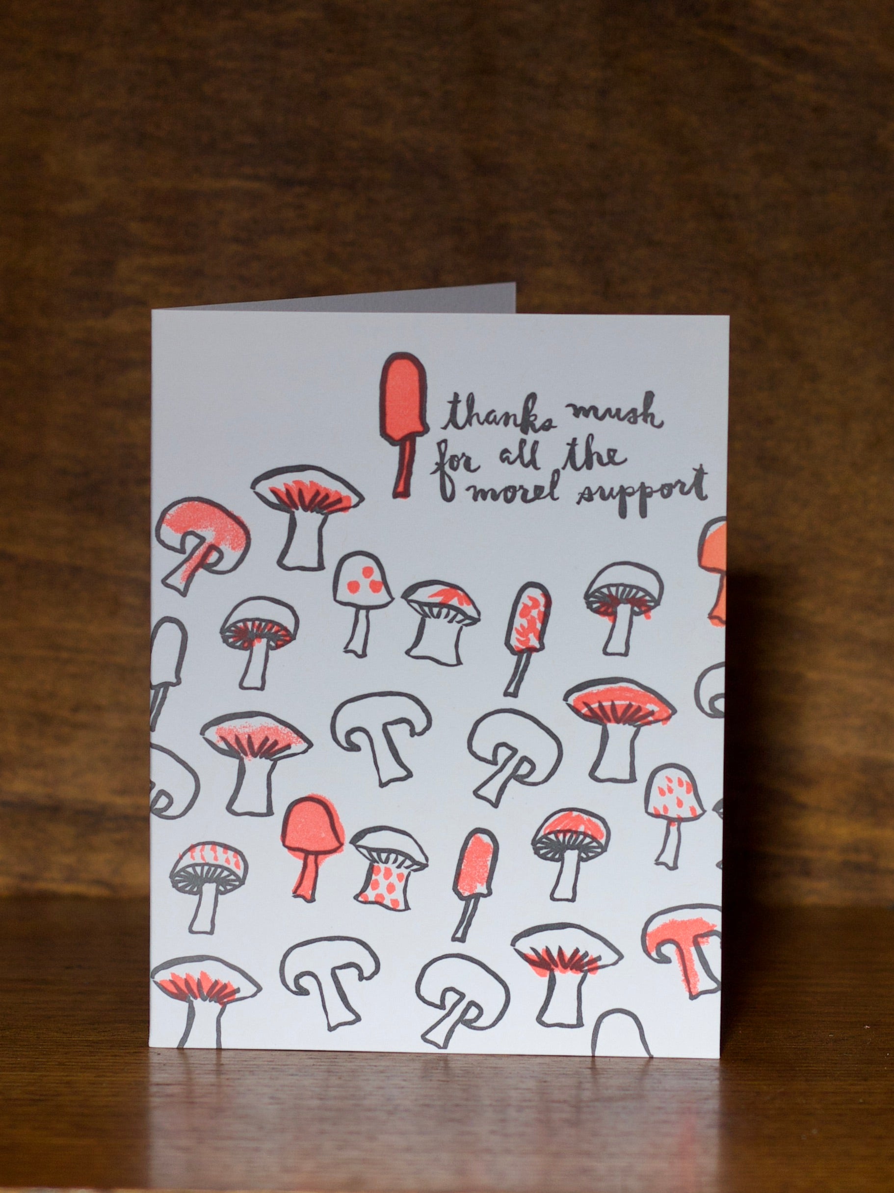 Thank you greeting card with mushroom illustrations and text on a wooden surface
