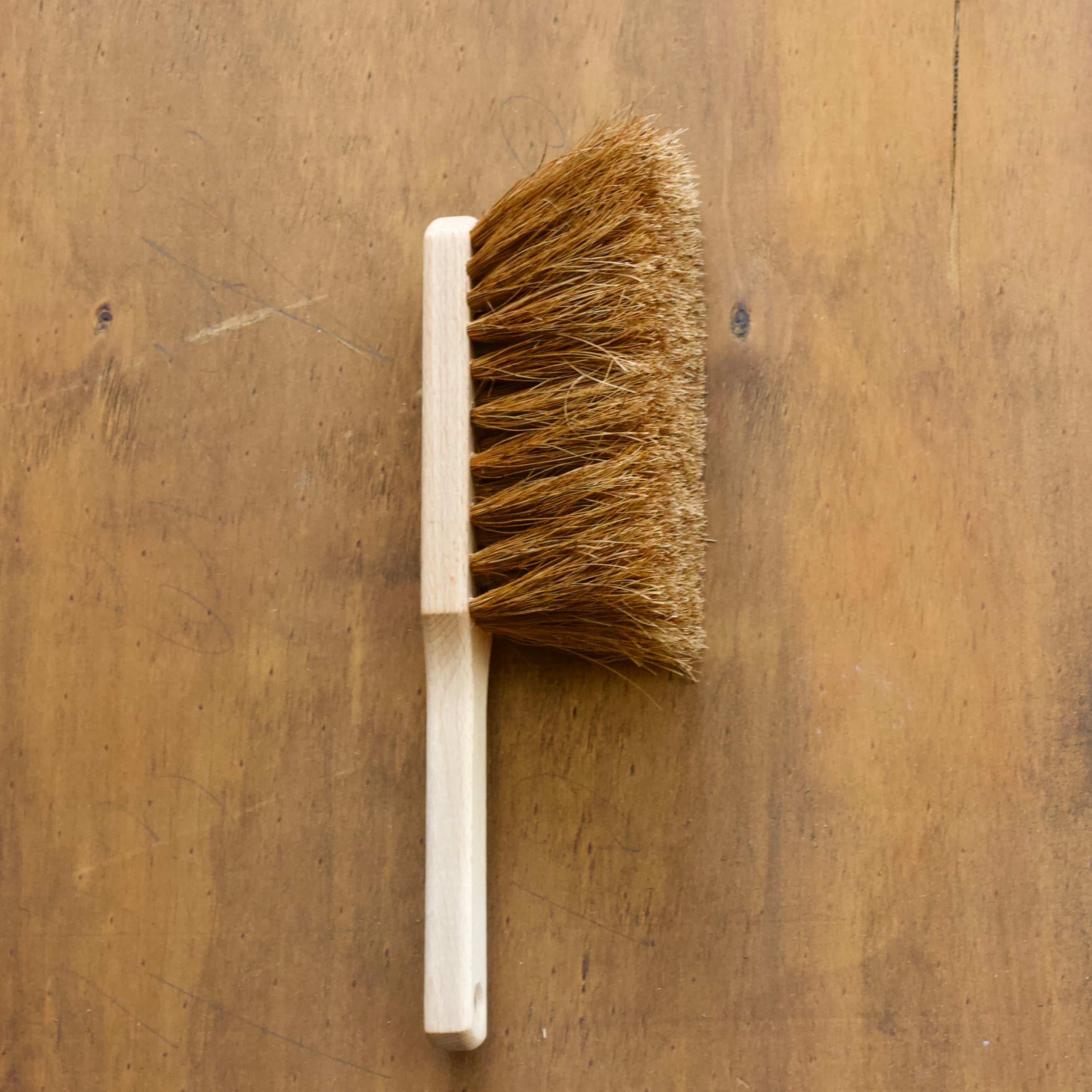 Hearth Brush made with coco fibres with wooden handle on a wooden surface
