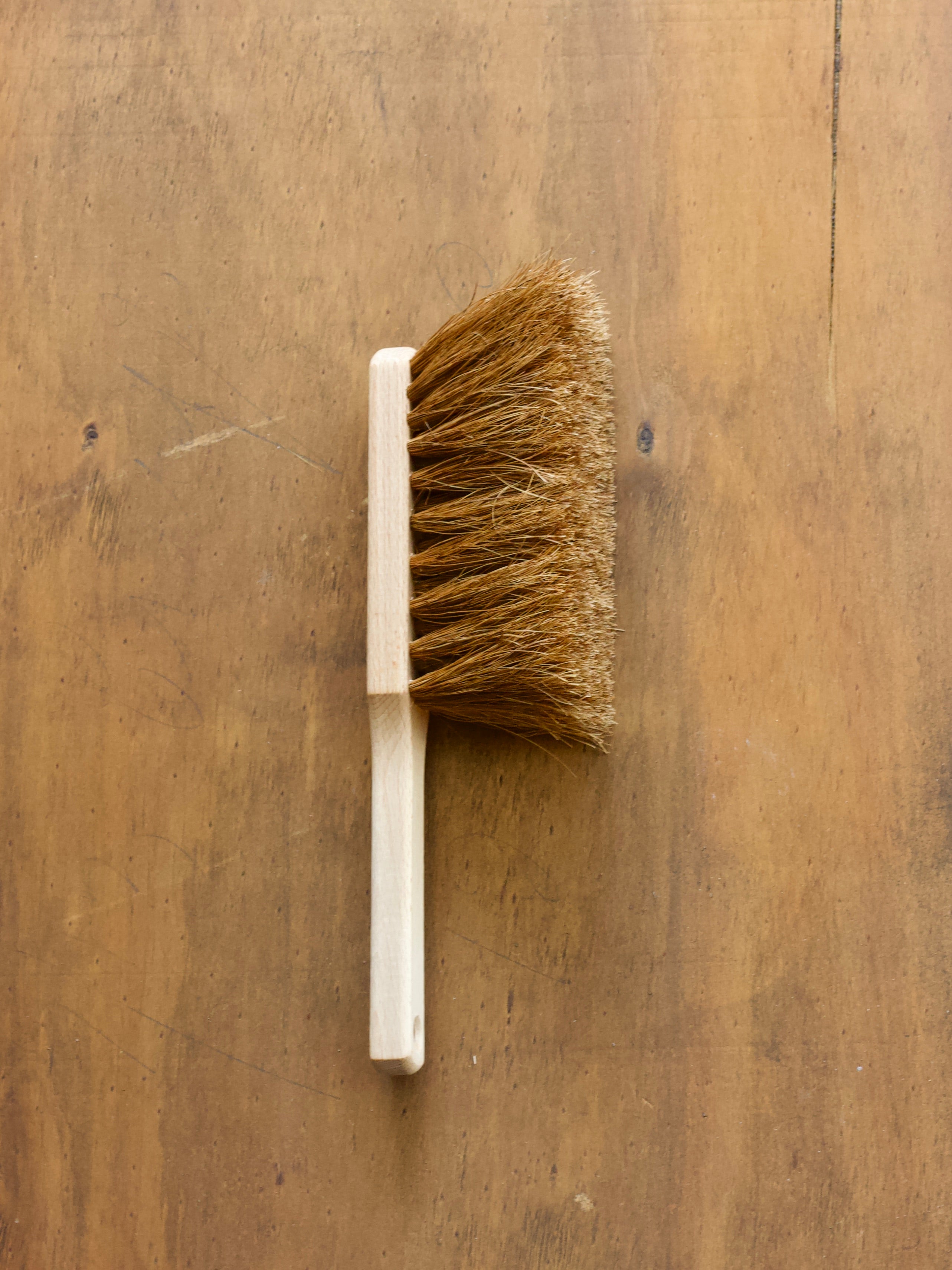 Hearth Brush made with coco fibres with wooden handle on a wooden surface