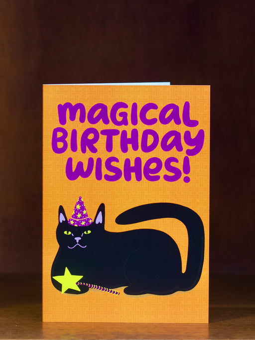 Birthday greeting card with a black cat wearing a party hat and 'Magical Birthday Wishes!' text on an orange  background