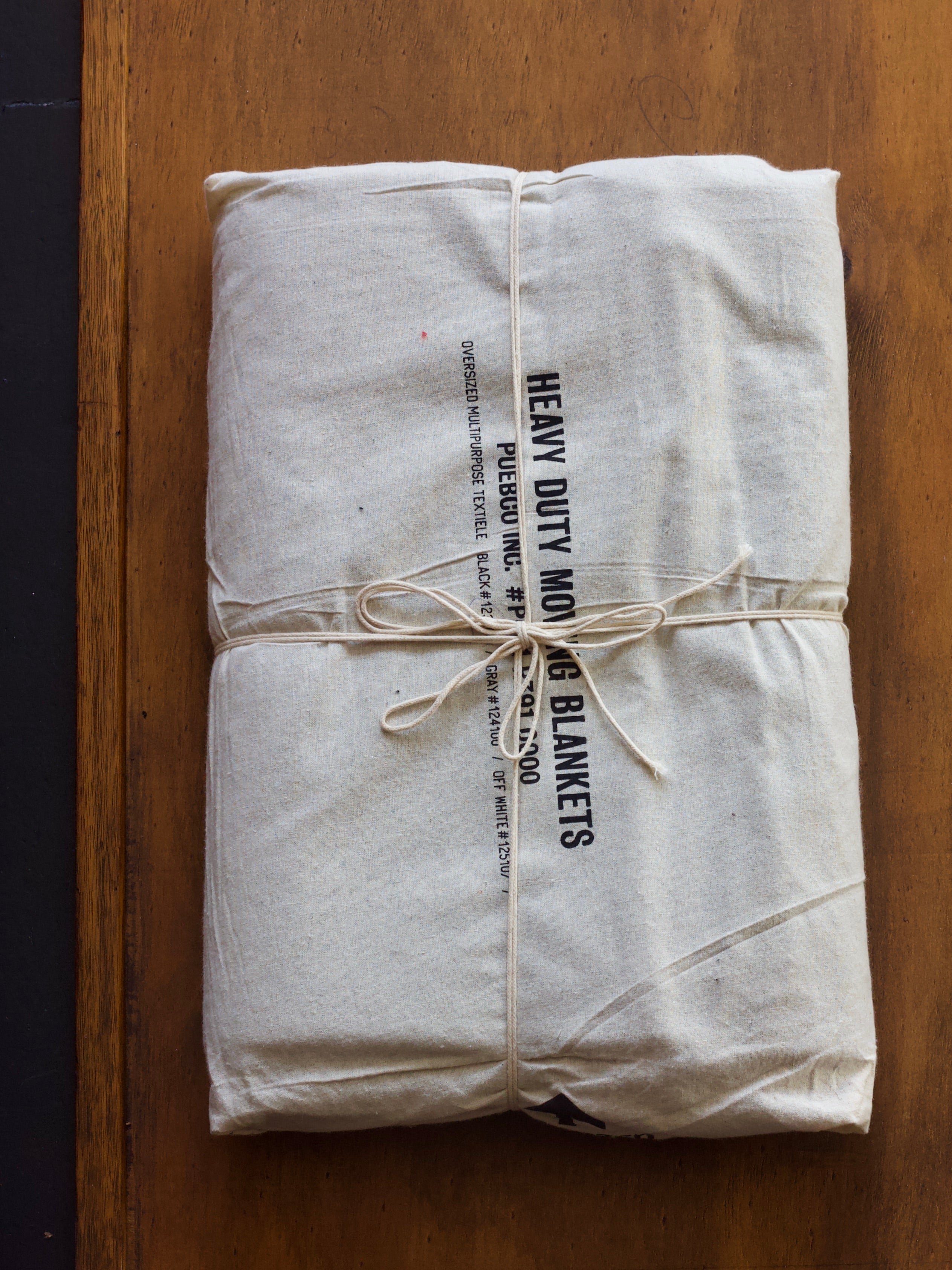 Heavy-duty moving blanket tied with string on a wooden surface