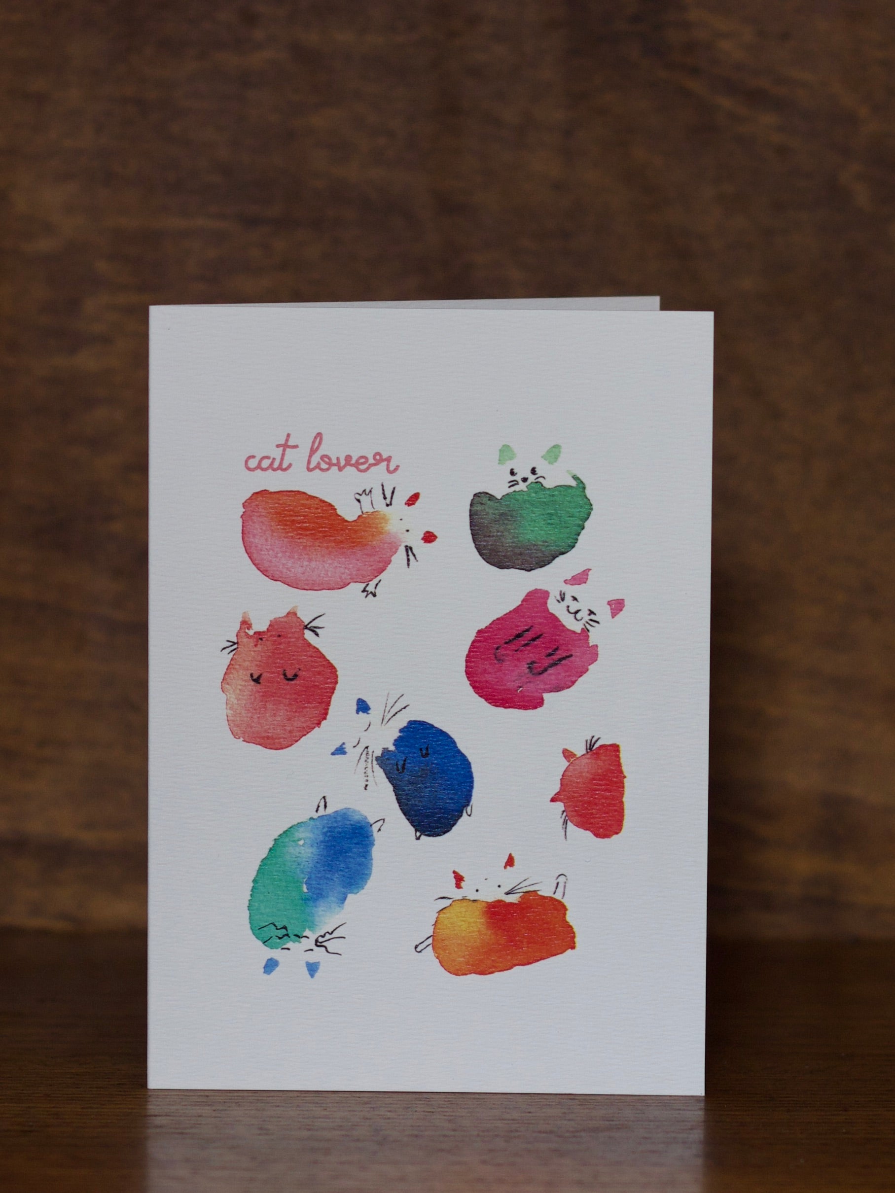 All Occasions greeting cards with colorful cat illustrations on a wooden surface