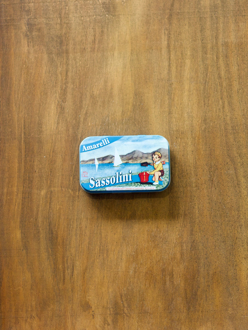Amarelli Sassolini Liquorice in a small tin box with a beach design on a wooden surface