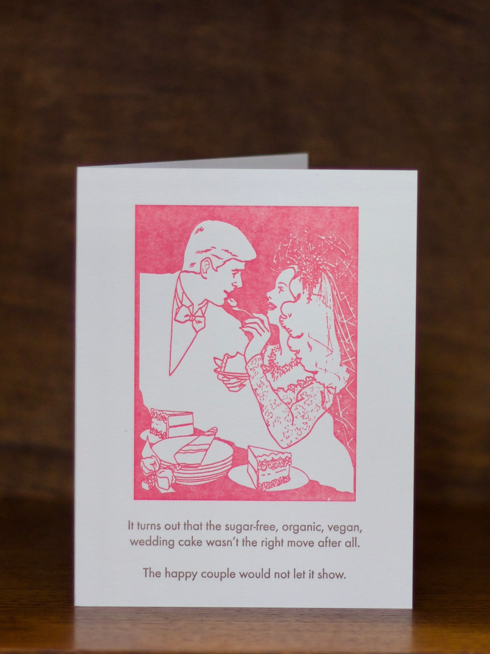 Wedding greeting card with a pink illustration of a couple and humorous text on a white background.