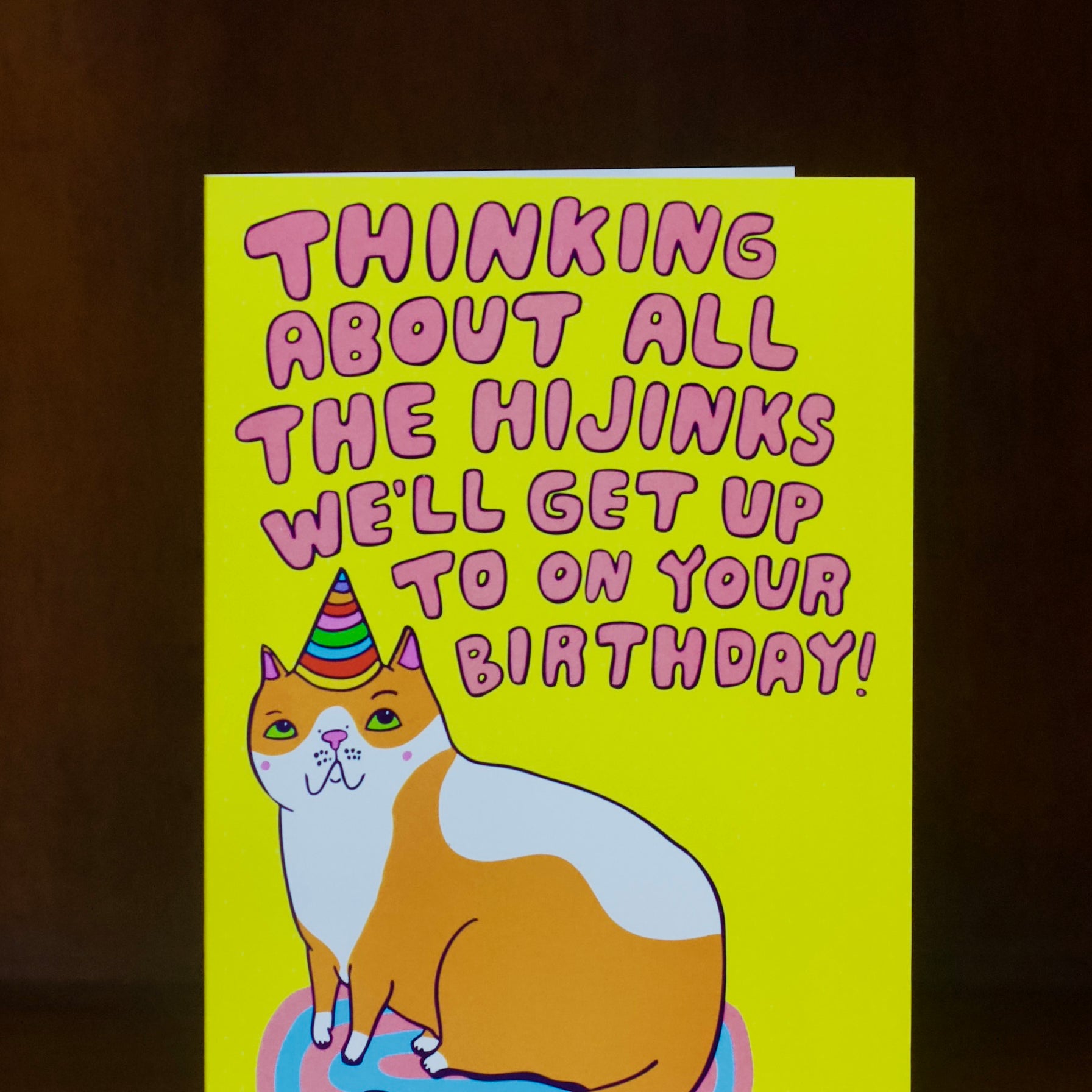 Birthday card with a cat illustration and humorous text on a yellow background