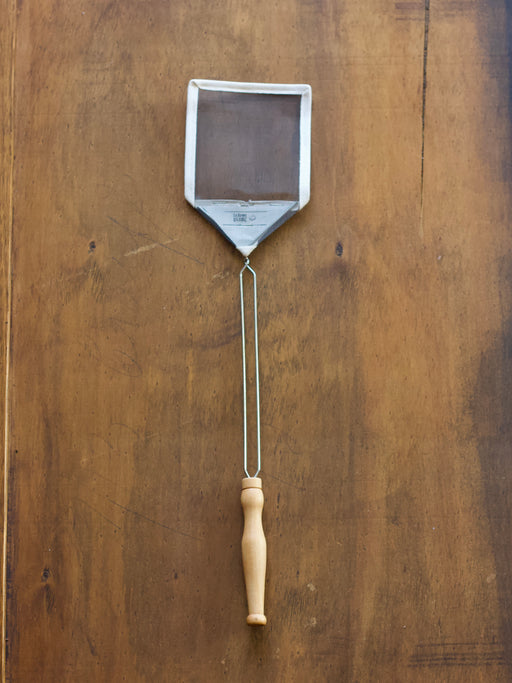 French Mesh Fly Swat swatter with a wooden handle on a wooden surface