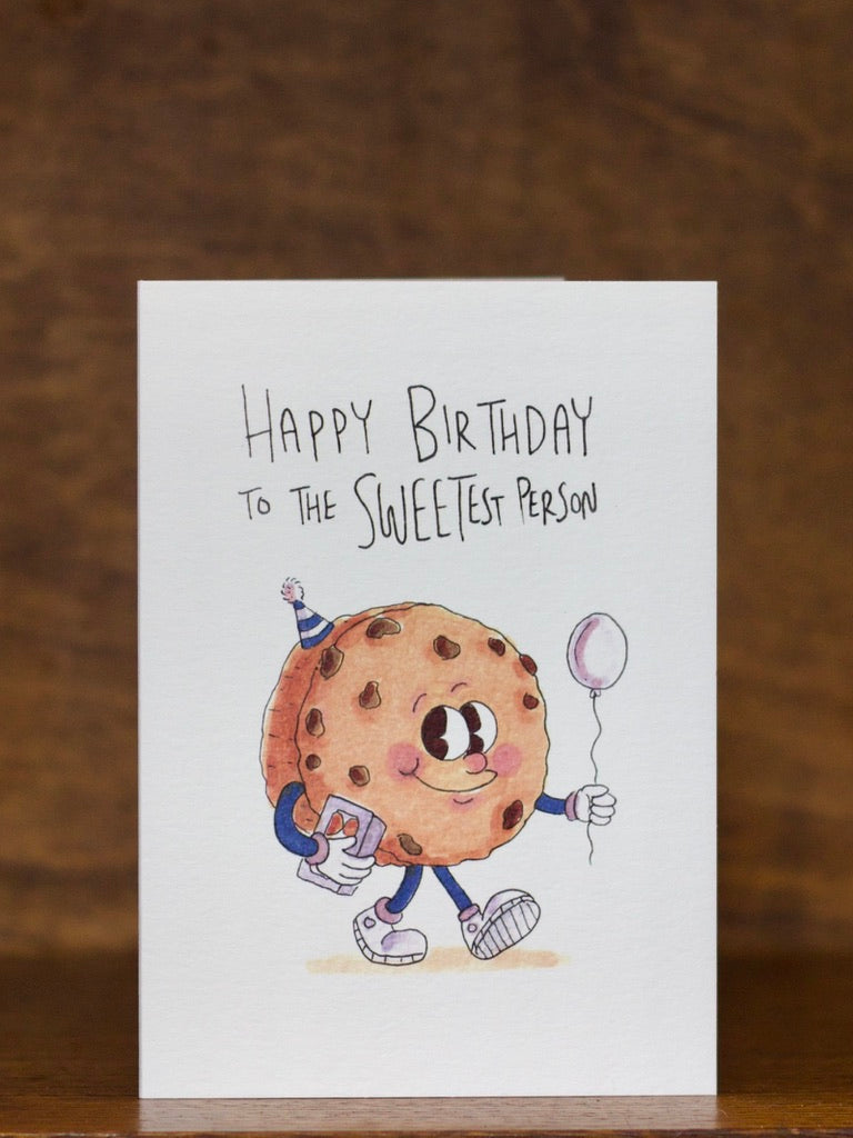 Birthday Greeting card by Well Drawn with a cartoon cookie character on a wooden surface