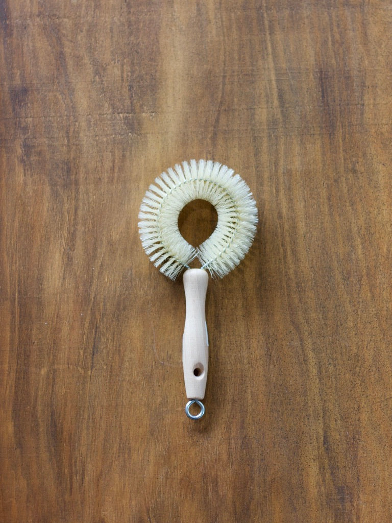 Redecker wine dish brush with a wooden handle on a brown wooden surface