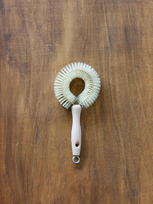 Redecker wine dish brush with a wooden handle on a brown wooden surface
