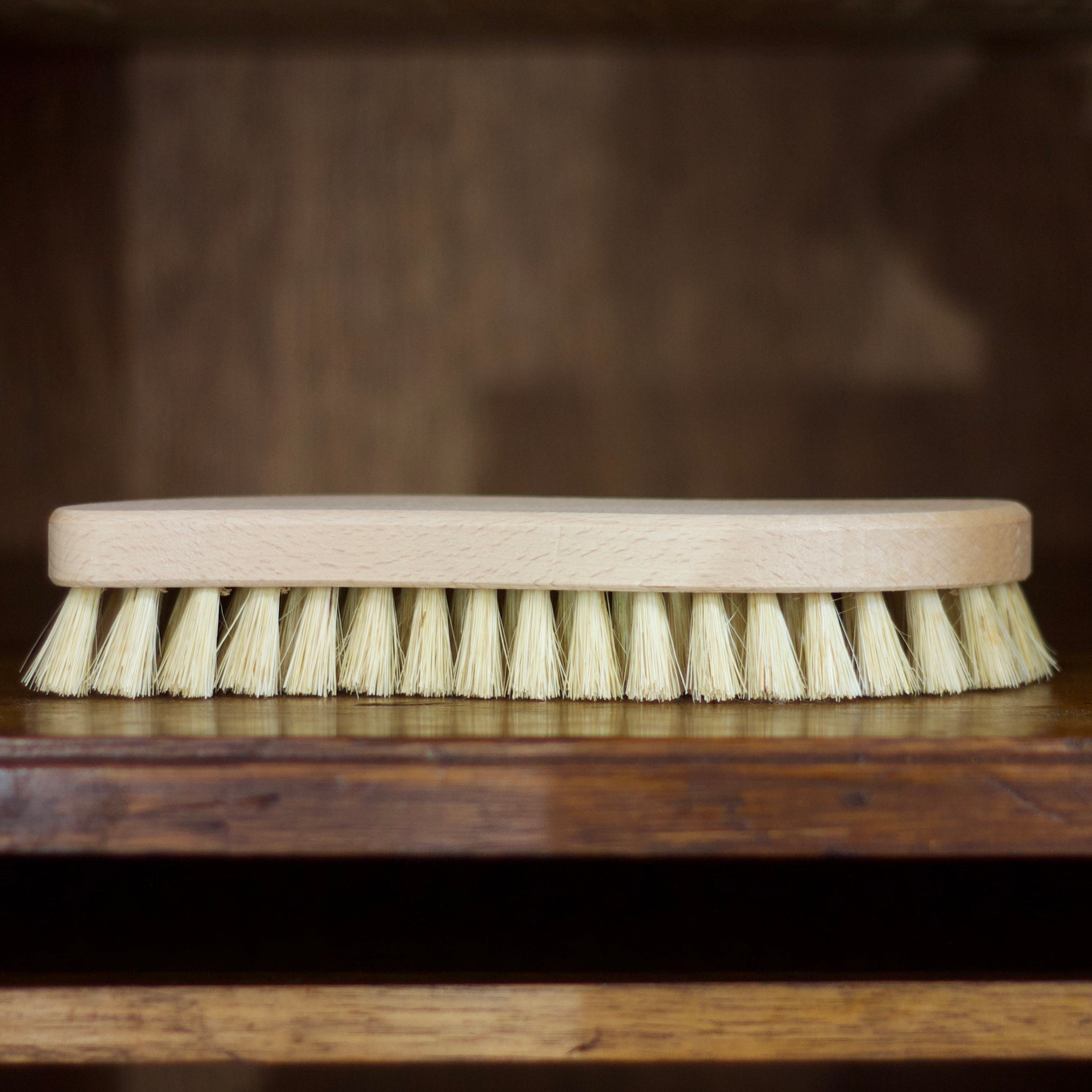 Cleaning brush with wooden handle and bristles on a wooden surface