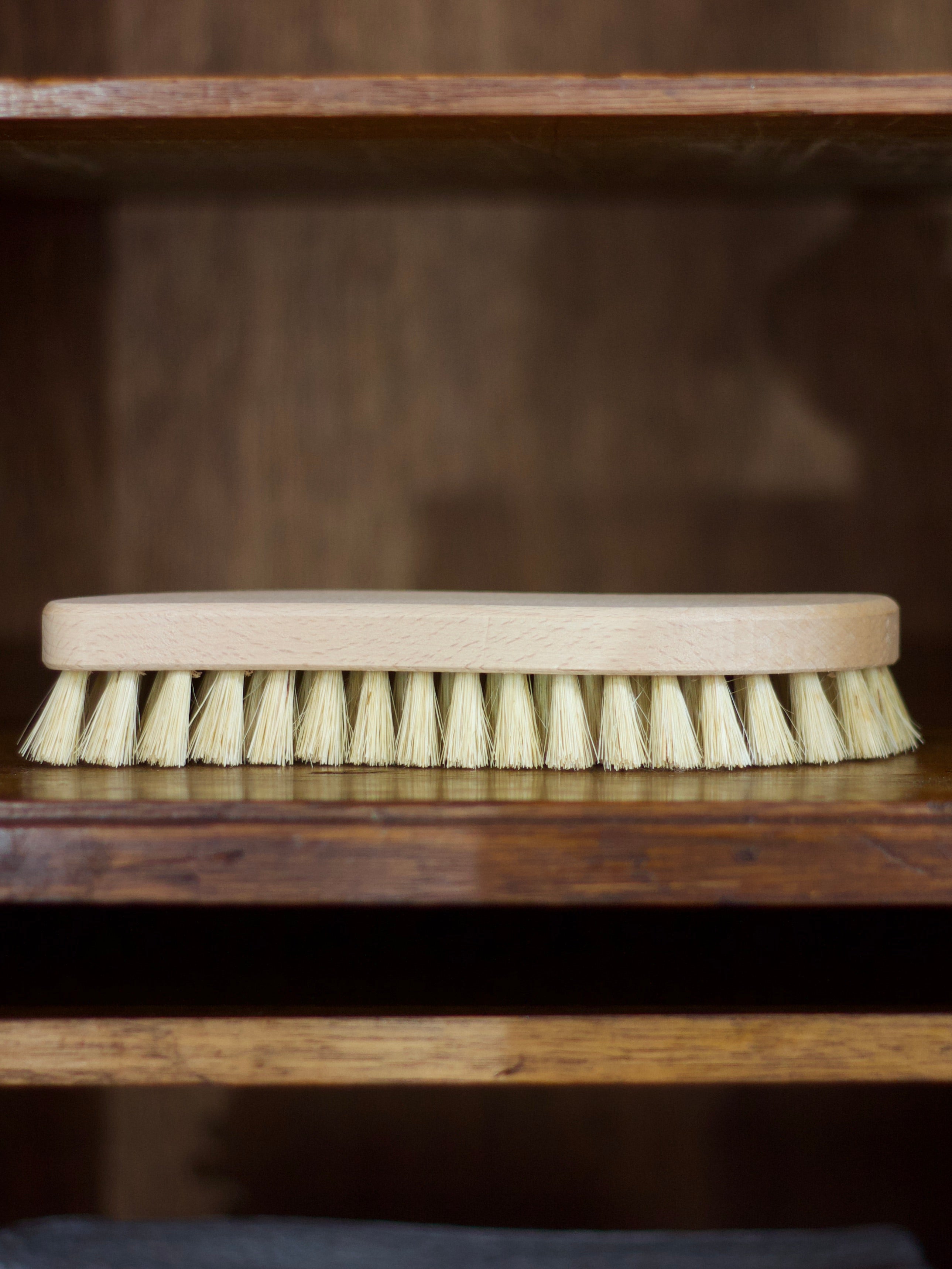Cleaning brush with wooden handle and bristles on a wooden surface