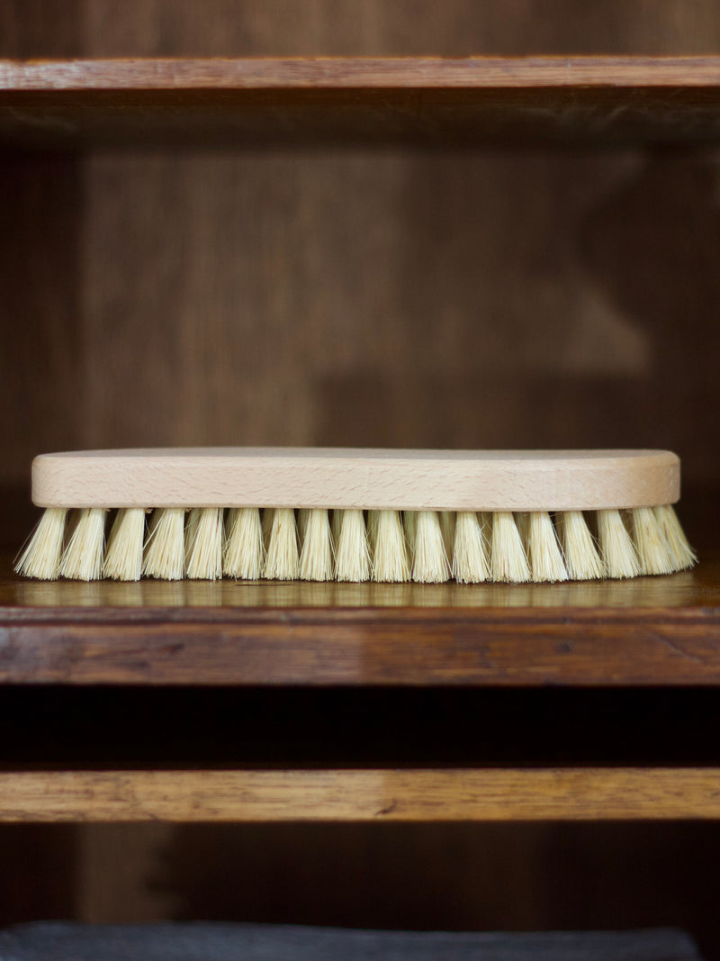 Cleaning brush with wooden handle and bristles on a wooden surface