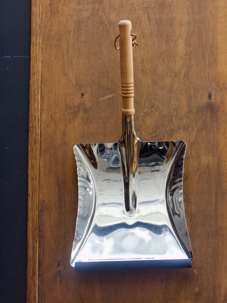 Redecker stainless steel dustpan with wooden handle on a wooden surface