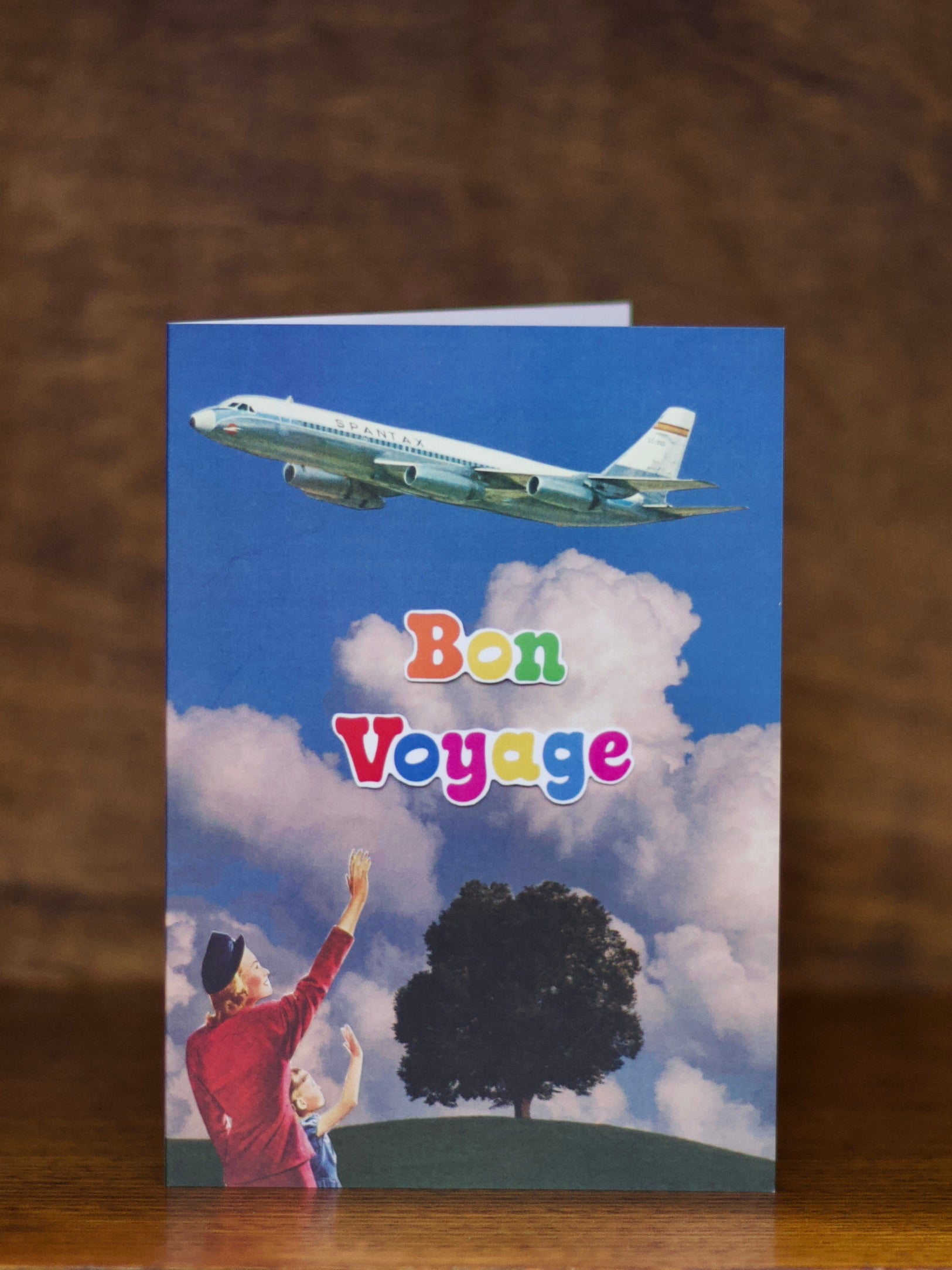 Bon Voyage greeting card with airplane and 'Bon Voyage' text against a blue sky with clouds.