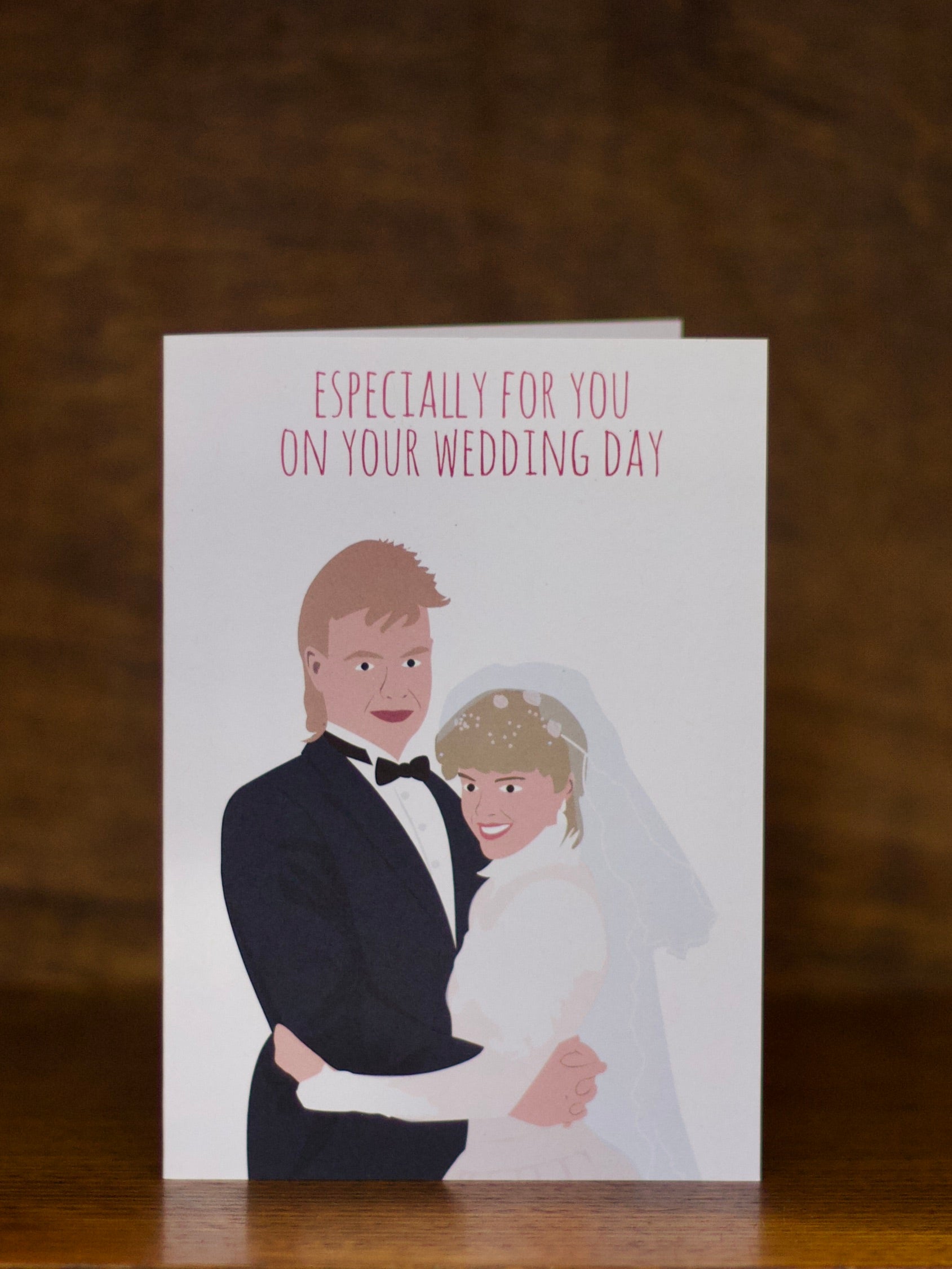 Wedding greeting cards with illustration of a bride and groom on a wooden surface