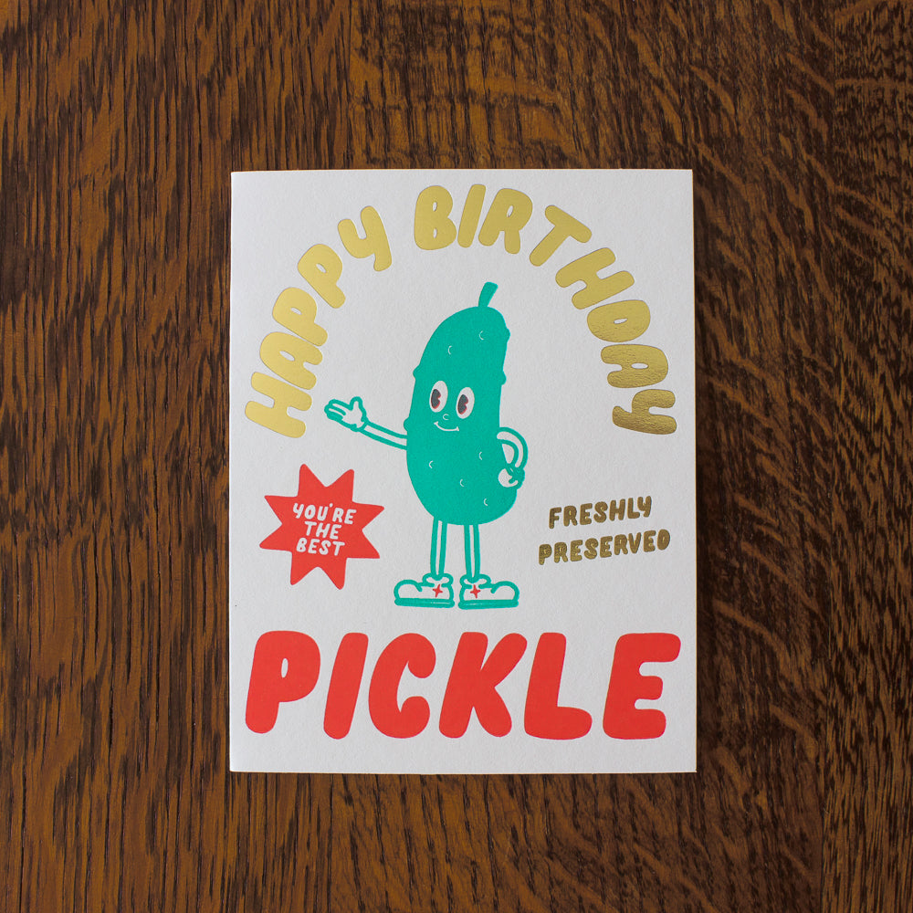 Birthday card with a pickle illustration on a wooden surface