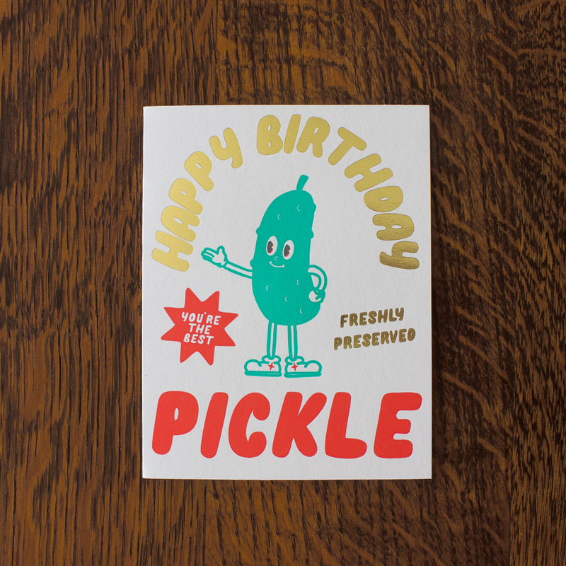 Birthday card with a pickle illustration on a wooden surface