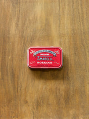Red tin with Amarelli Rossano liquorice branding on a wooden surface