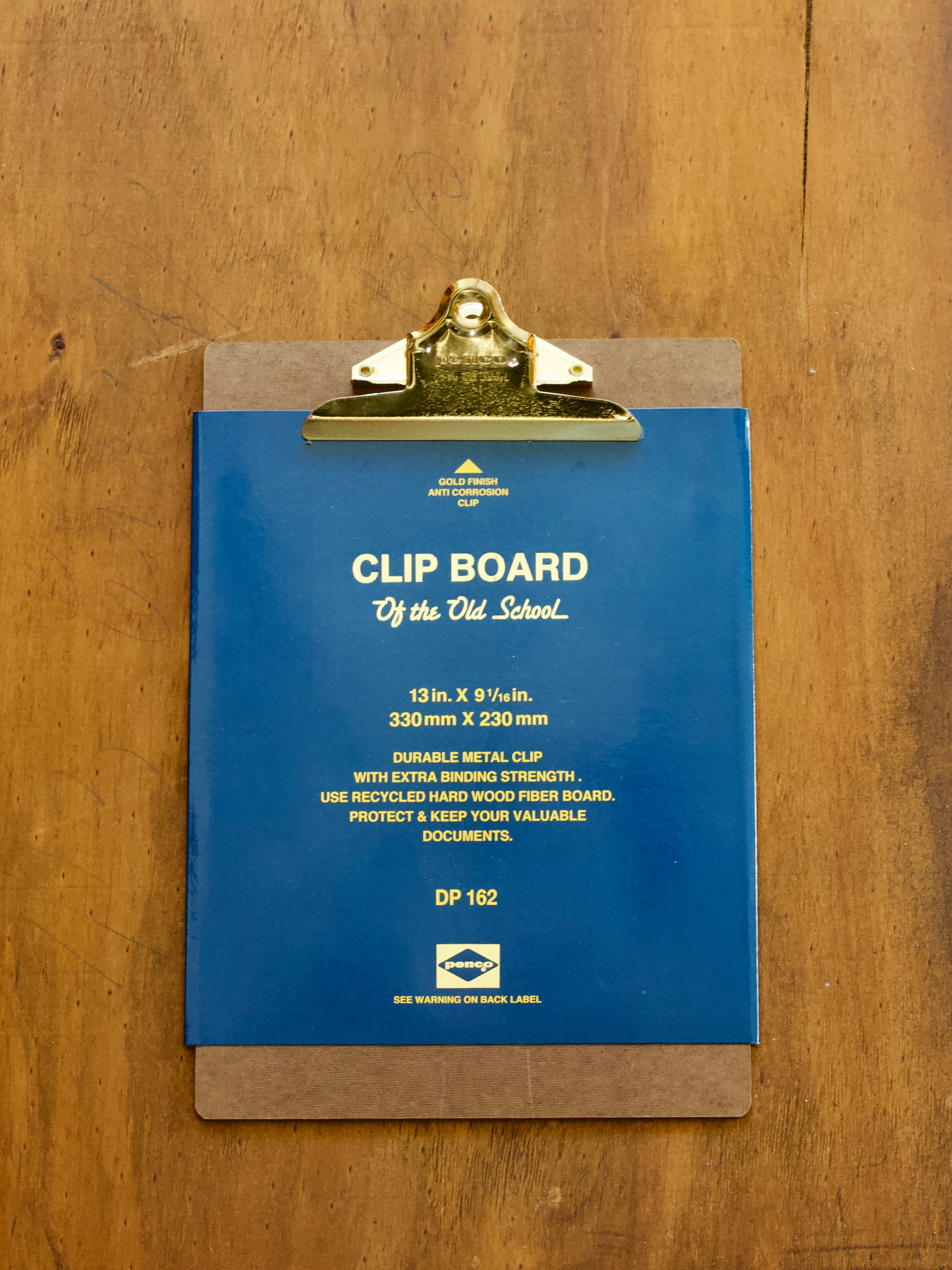 Penco old school clipboard with gold coloured clip on a wooden surface