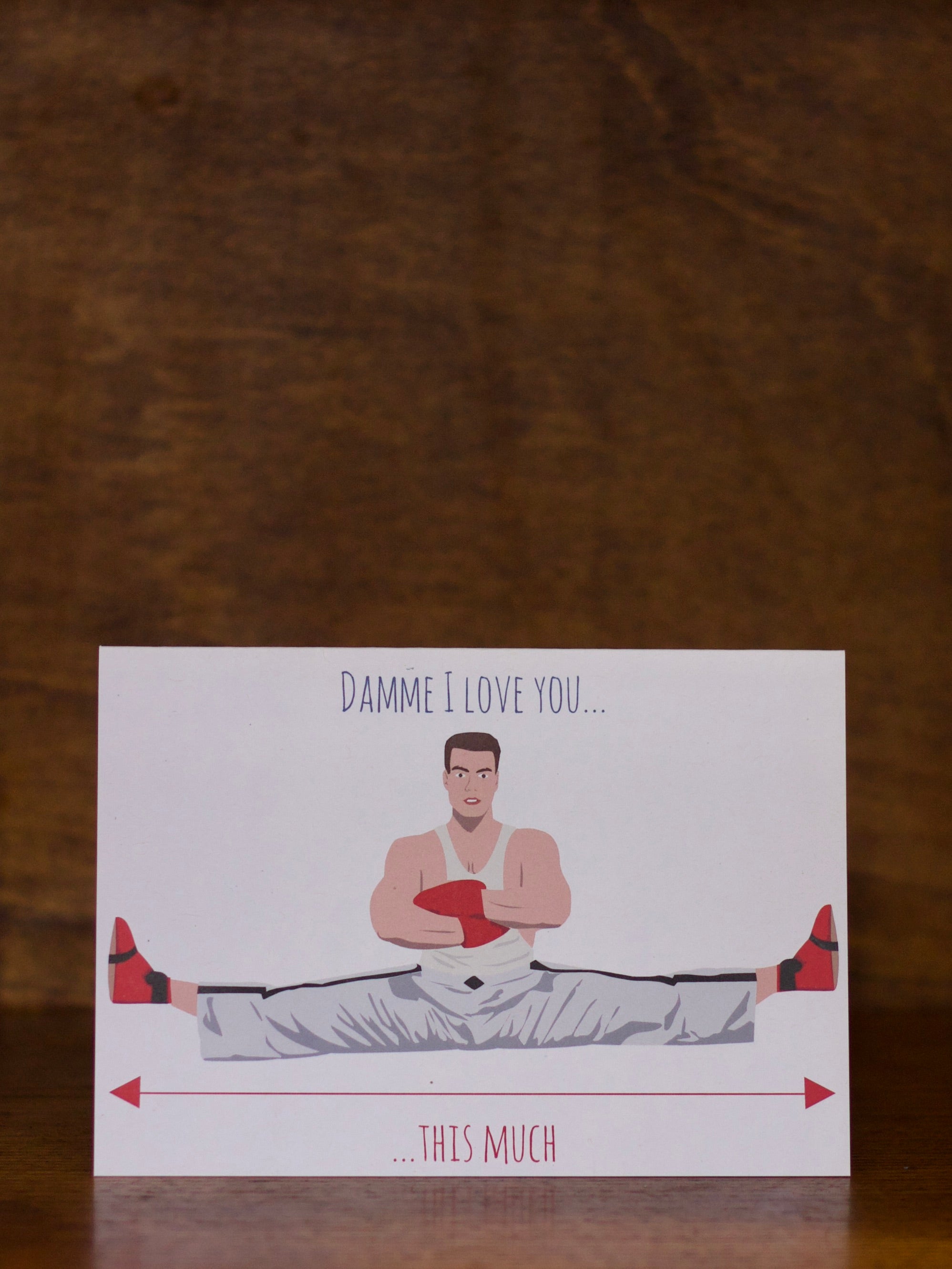 Love & Friendship greeting card with a cartoon illustration of a person in a splits pose and text on a wooden surface