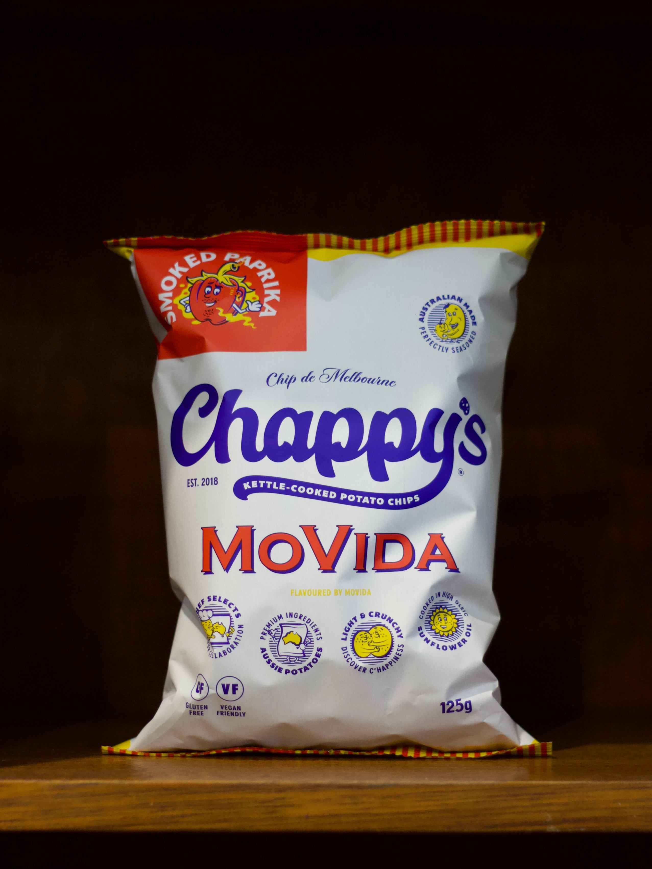 Bag of Smoked Paprika Flavoured Chappy's kettle-cooked potato chips on a wooden surface with a dark background