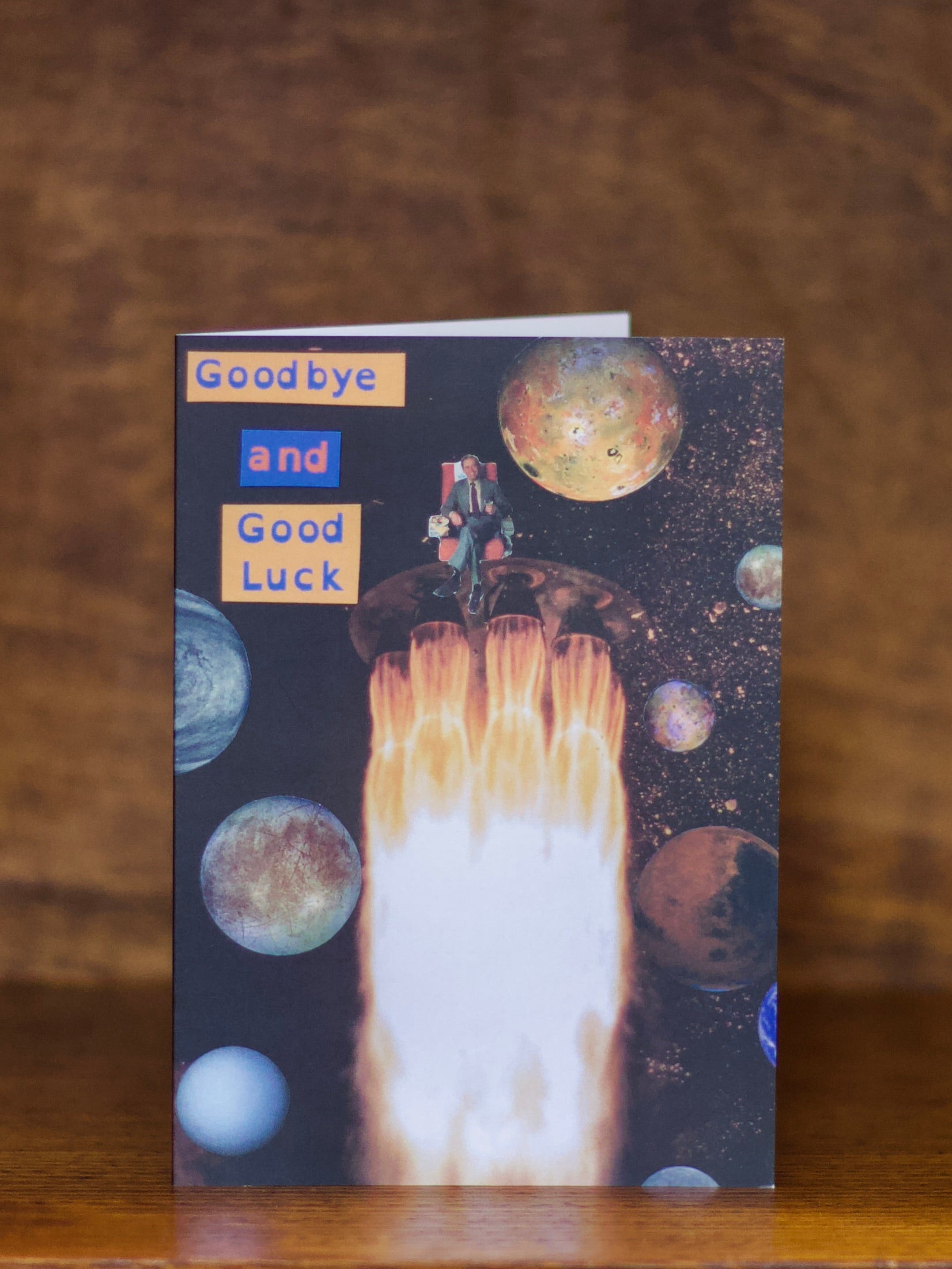 Goodbyr and good luck greeting card with a rocket and planets design on a wooden surface